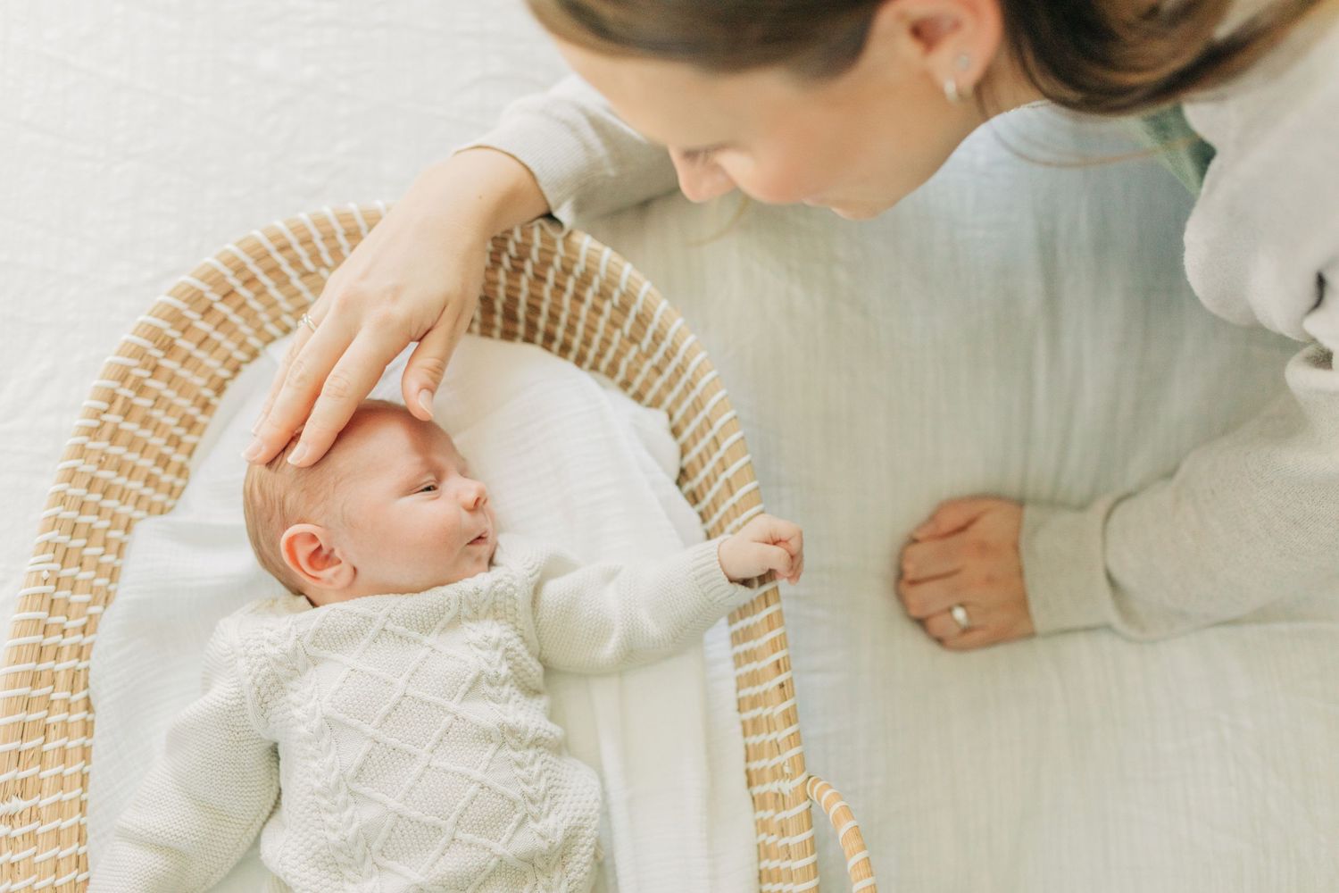 Gentle close-up shots of parent and baby in soft white knit clothing.