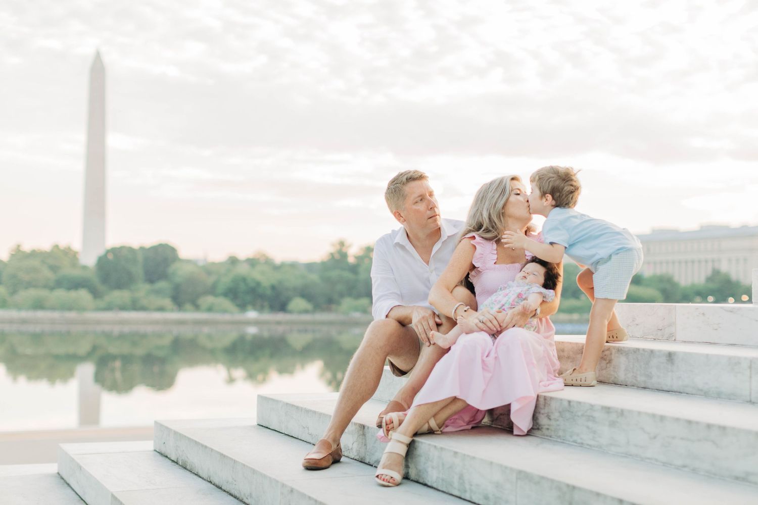 Family sitting together on white stone steps during sunset photoshoot.