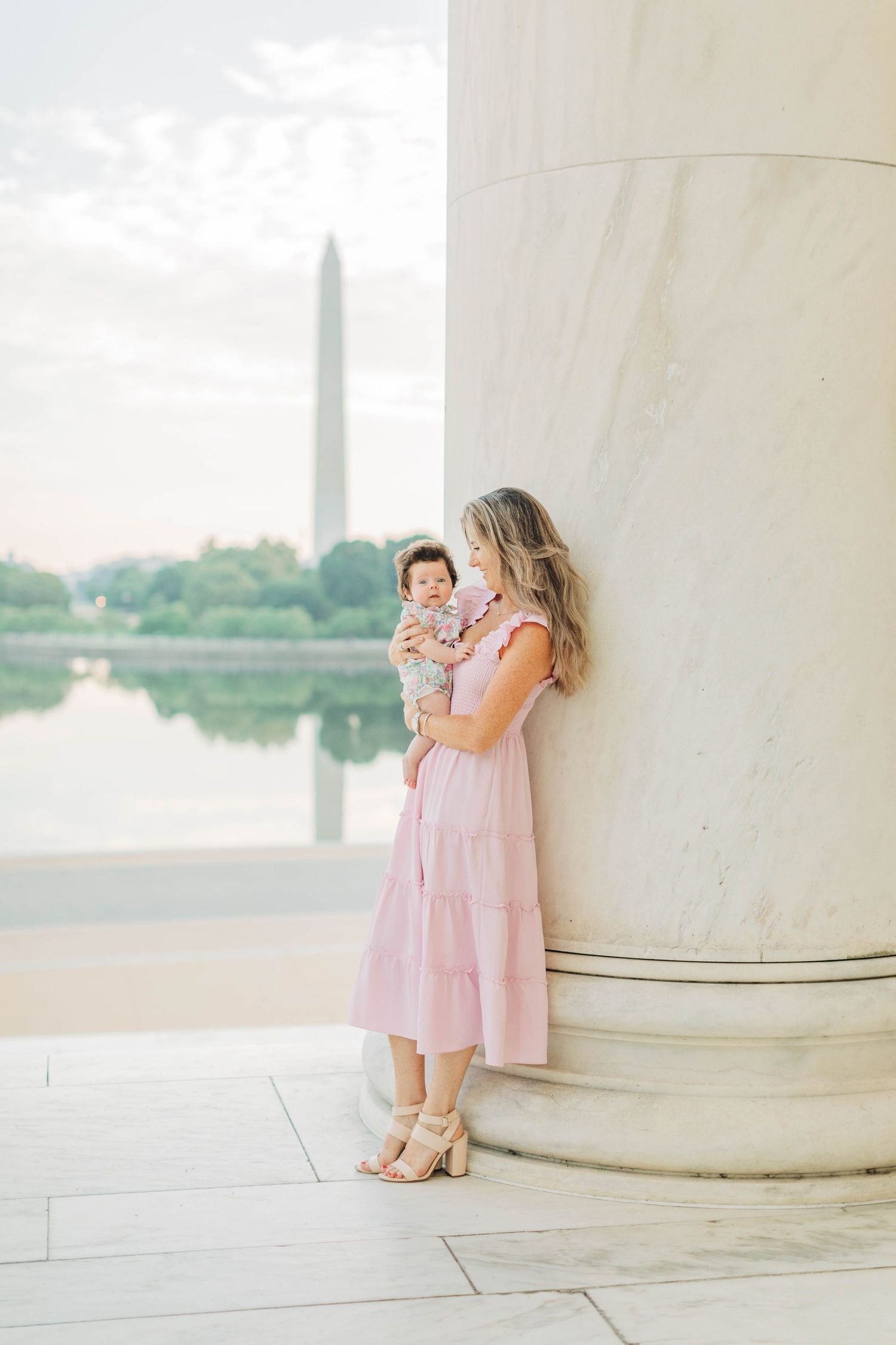 Elegant portrait by a marble column at the Jefferson Memorial with DC monuments in view.