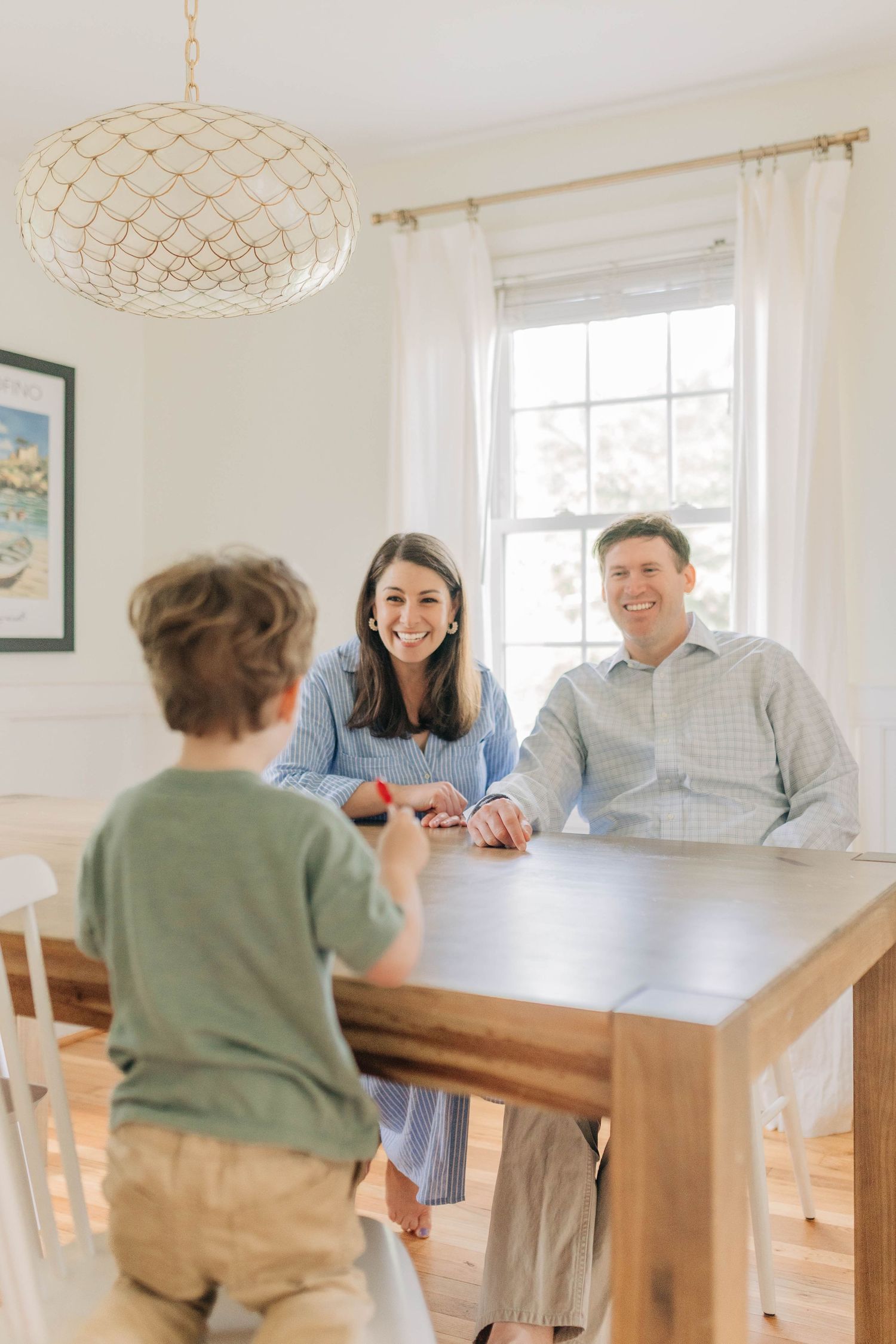 Family sharing a moment around a wooden dining table in a bright, airy room.