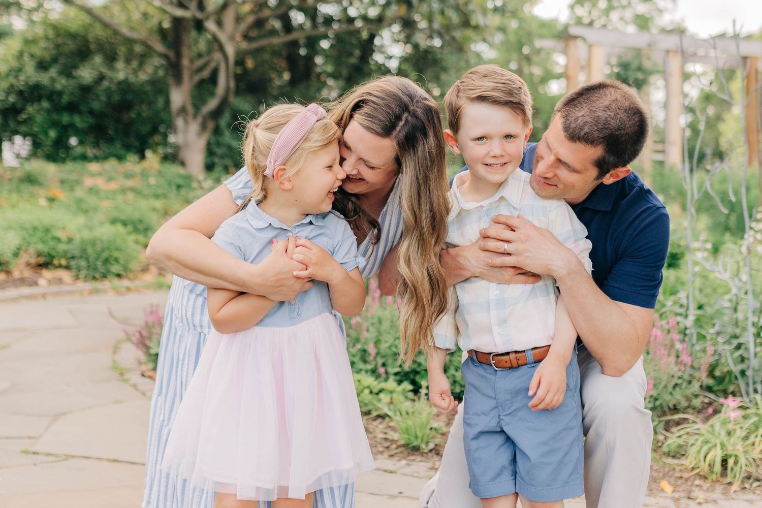 Family sharing tender moments and embraces in a sunlit garden setting.