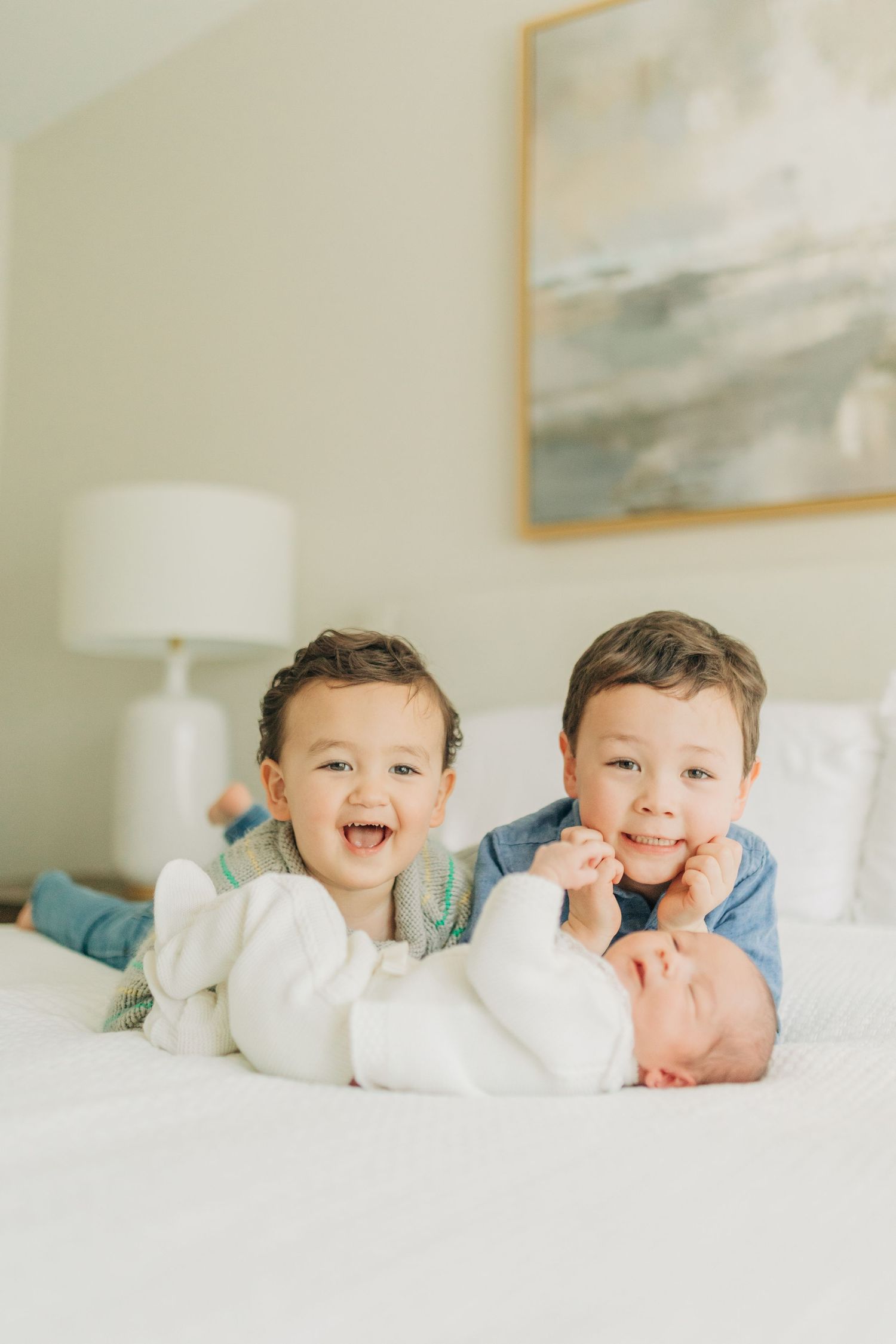 Children share laughs and smiles while relaxing together on white bedding.