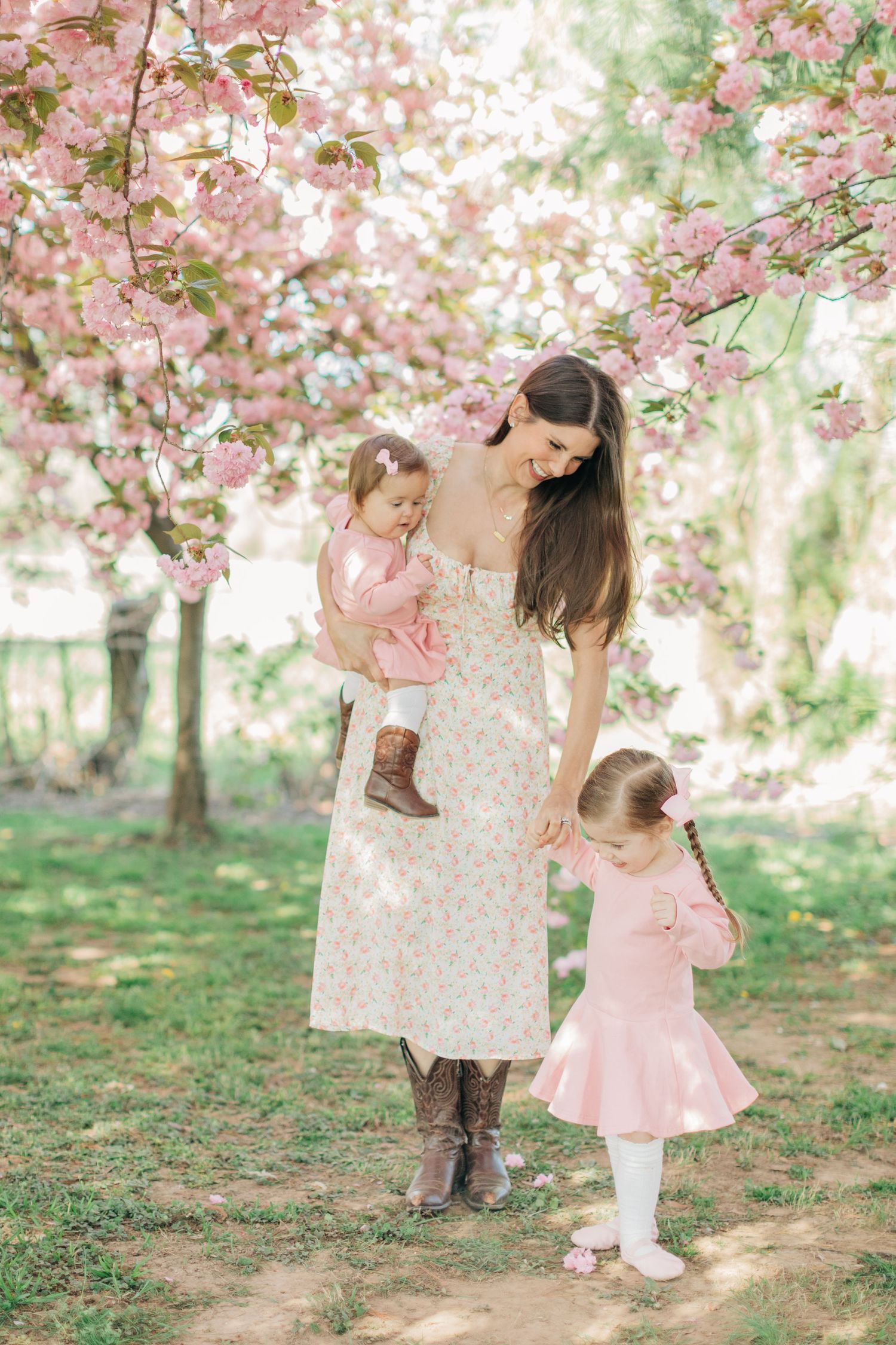A springtime family portrait under cherry blossoms with coordinating pink and floral outfits.