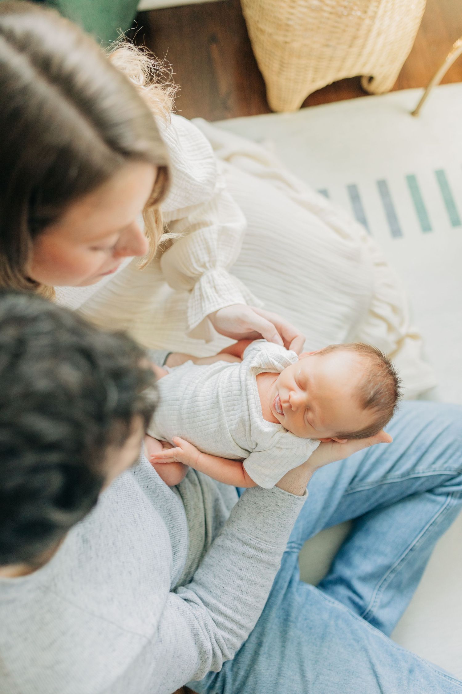 Parents gaze adoringly at their newborn baby while relaxing in a bright nursery.