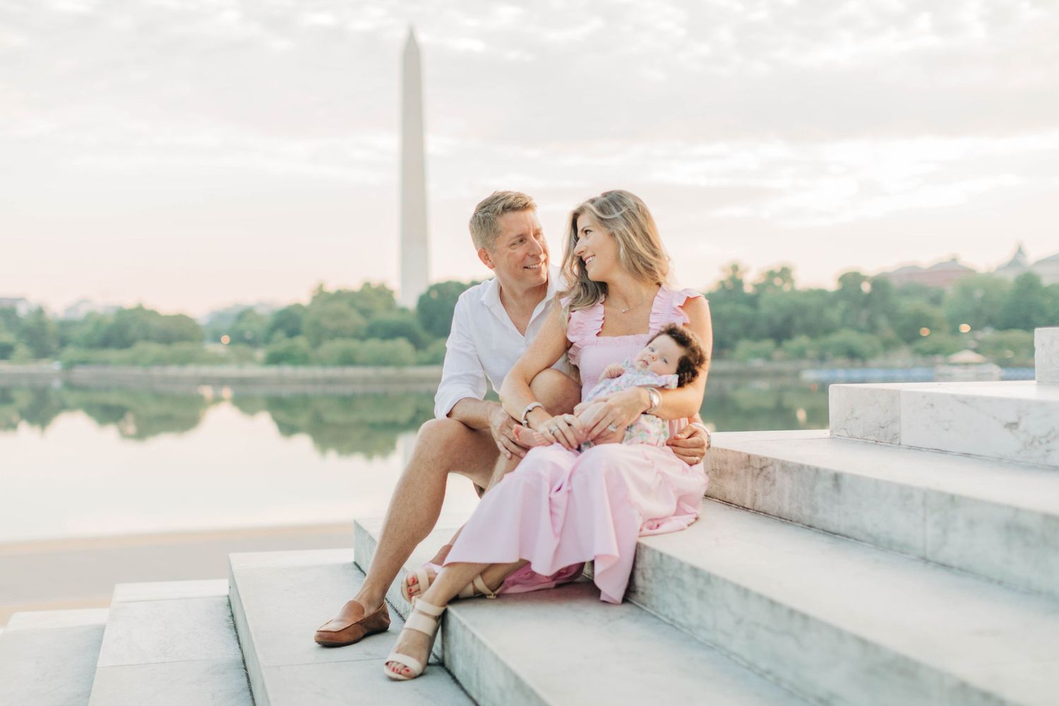 Family sharing tender moments on stone steps with Washington Monument in background.