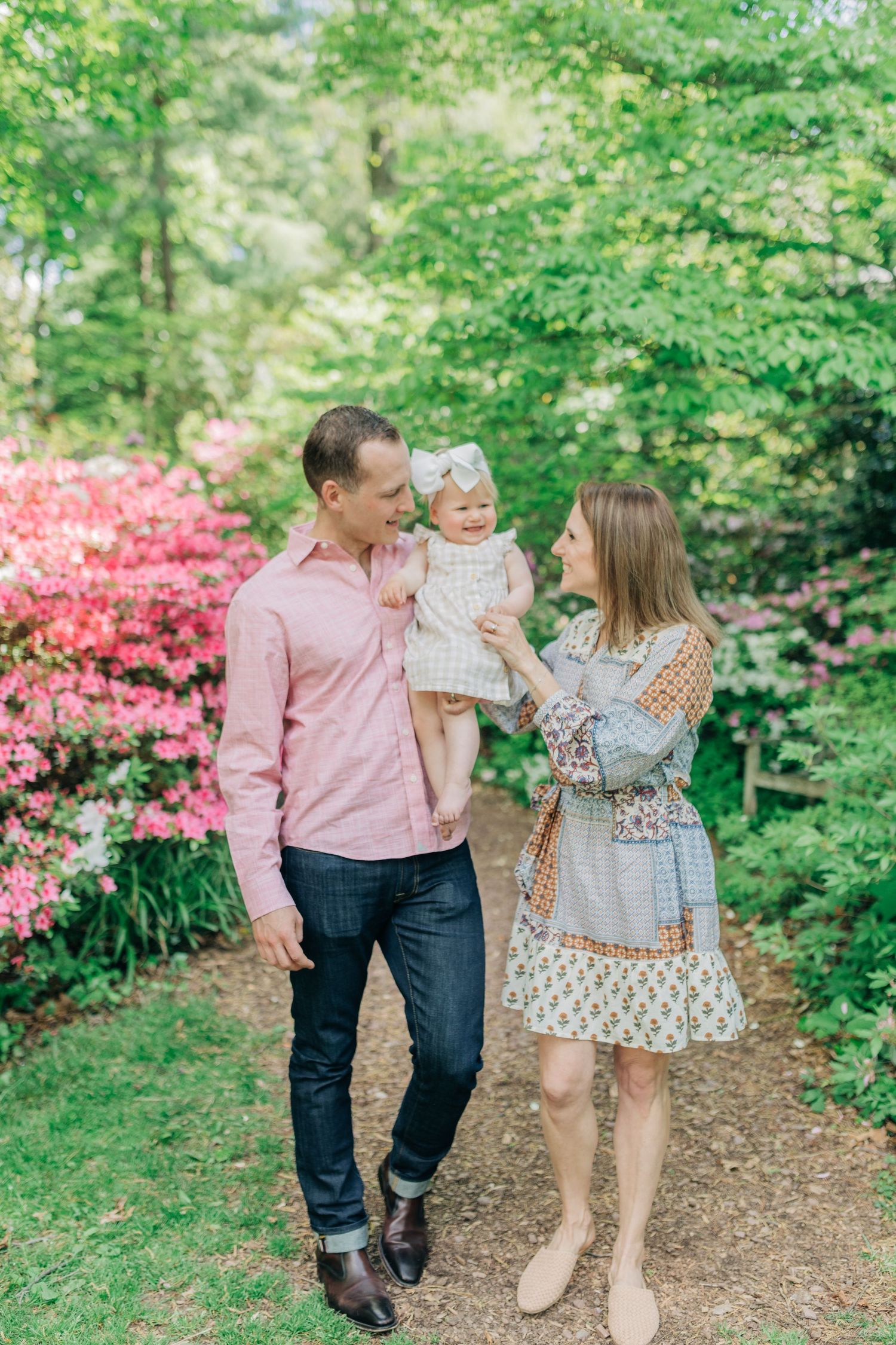 Family walking together on mulch path surrounded by spring greenery and pink flowers.