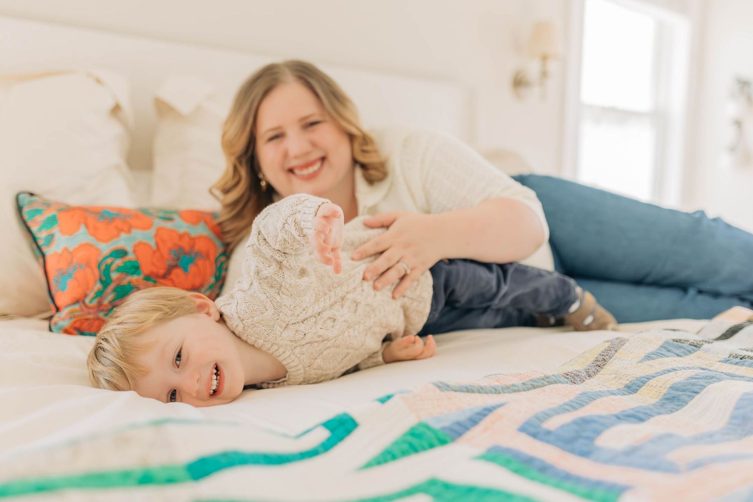Cozy lifestyle photos of family relaxing together on a white bed with soft natural lighting.