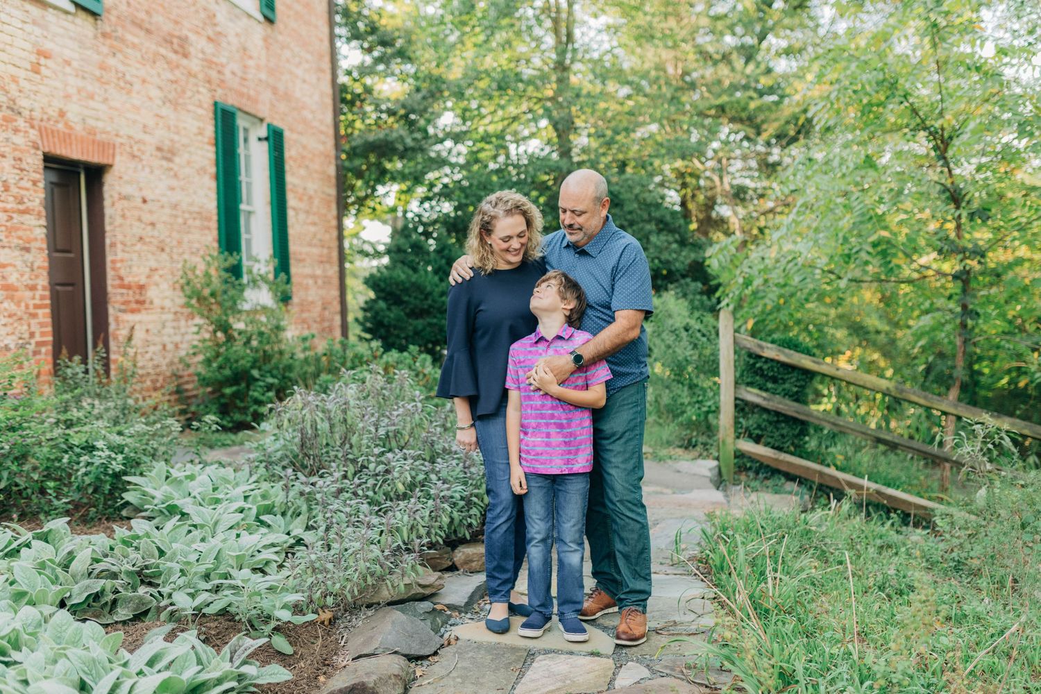 Family members stand together on a stone pathway with a historic brick building and garden in the background.