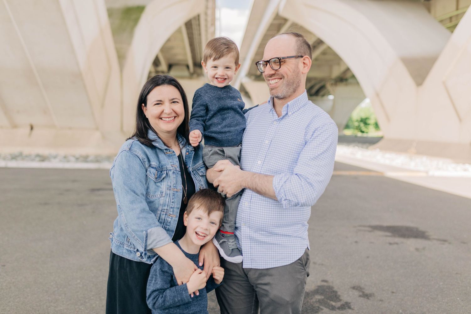 Family enjoying a playful moment together under white architectural arches outdoors.