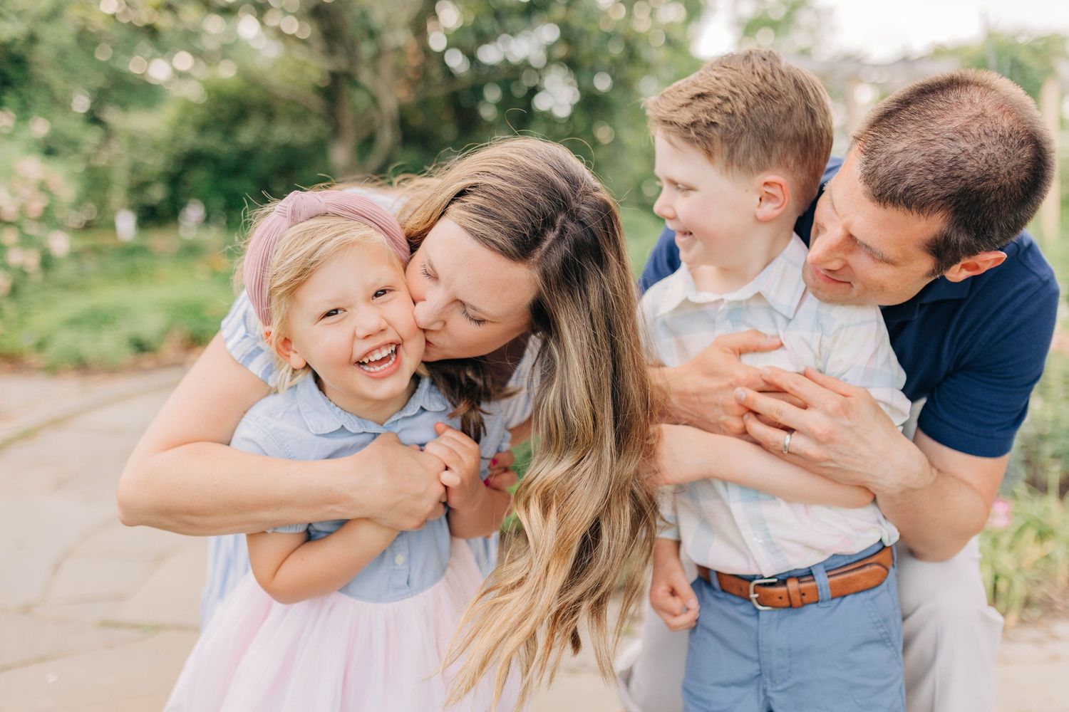 Candid family photography session showing joyful embraces in an outdoor garden.