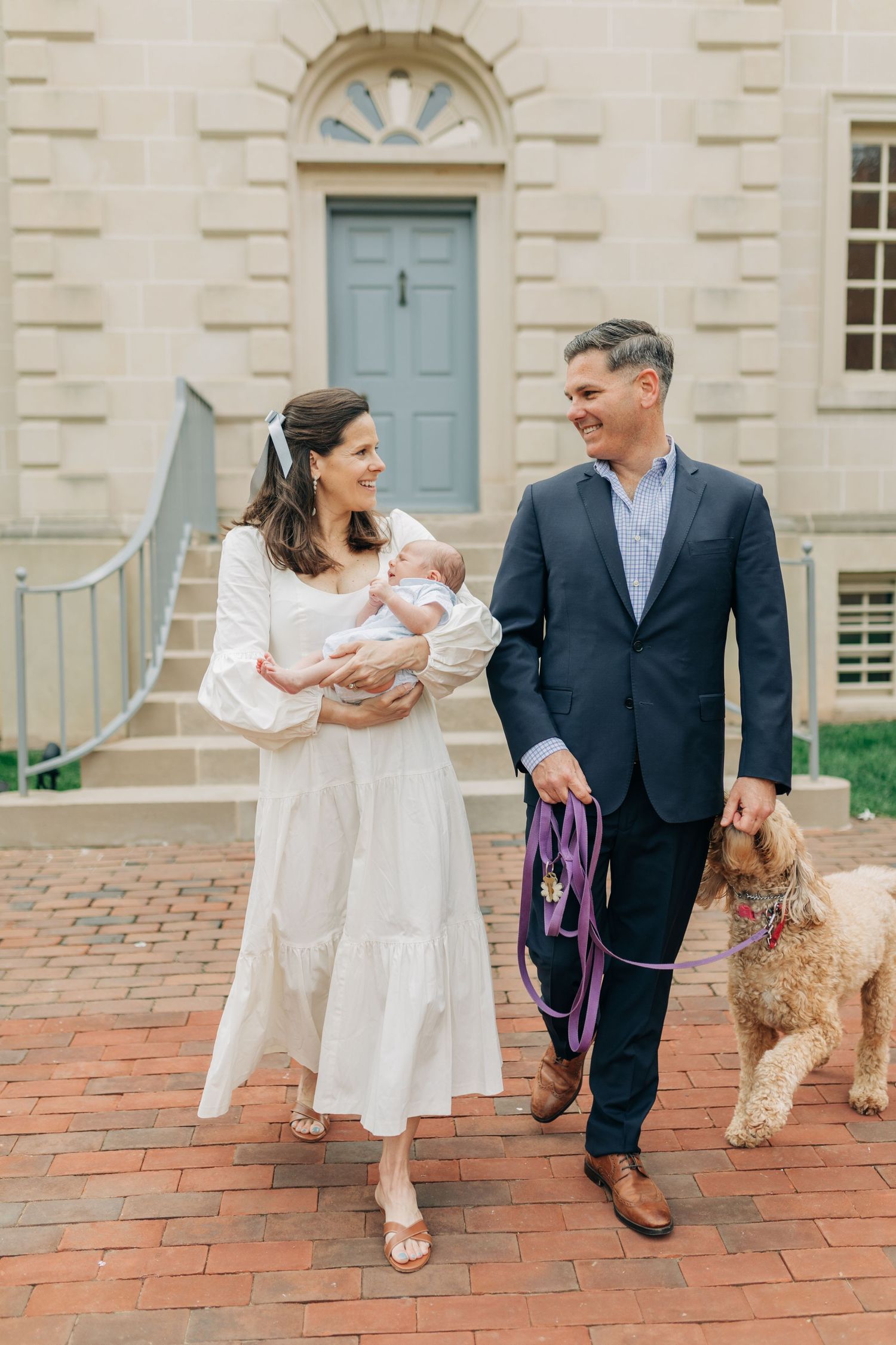 Casual family portraits with dog on brick patio near historic building entrance.