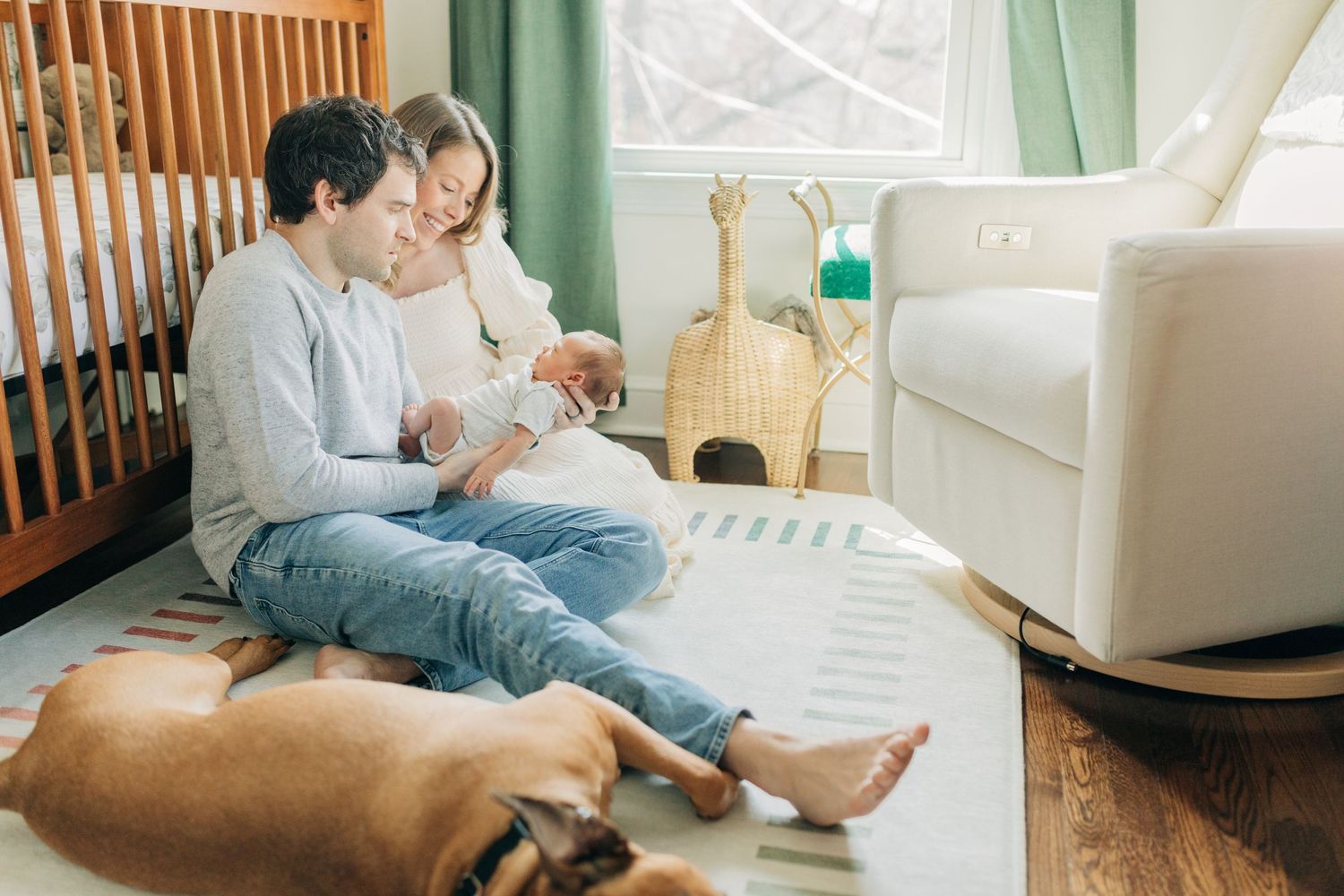 Modern nursery setting with wooden crib and green curtains during family photoshoot.
