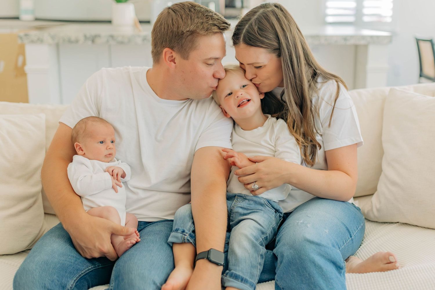 A family shares an intimate moment together on a white couch.