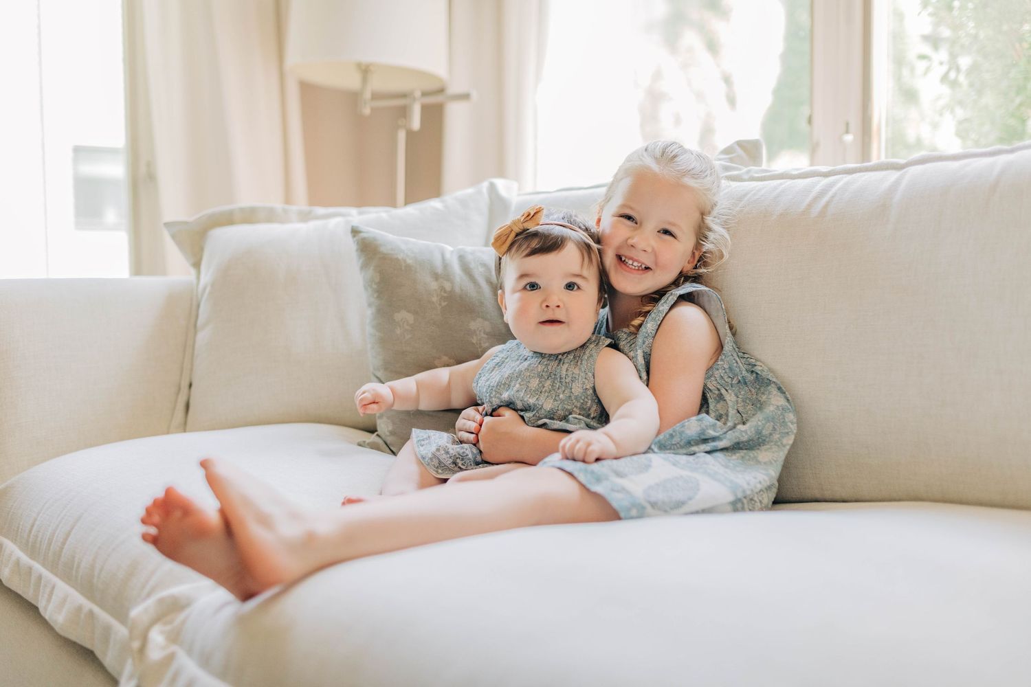 Casual family lifestyle moments captured on a white couch in natural light.