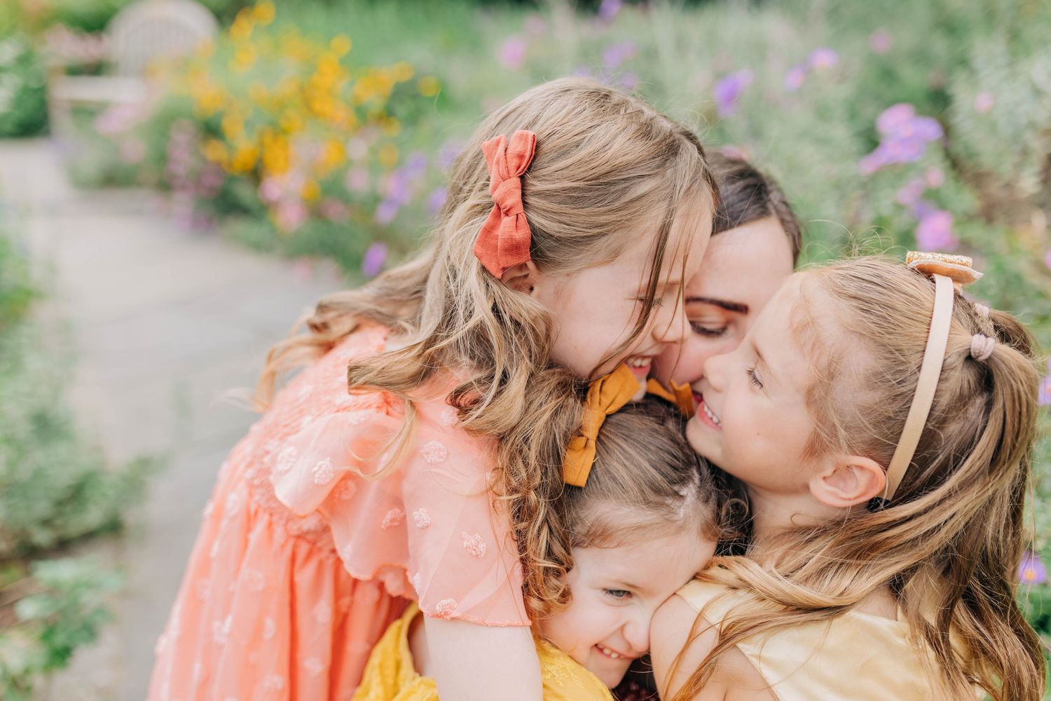Mother and child sharing tender moments among blooming flowers in soft peach tones.