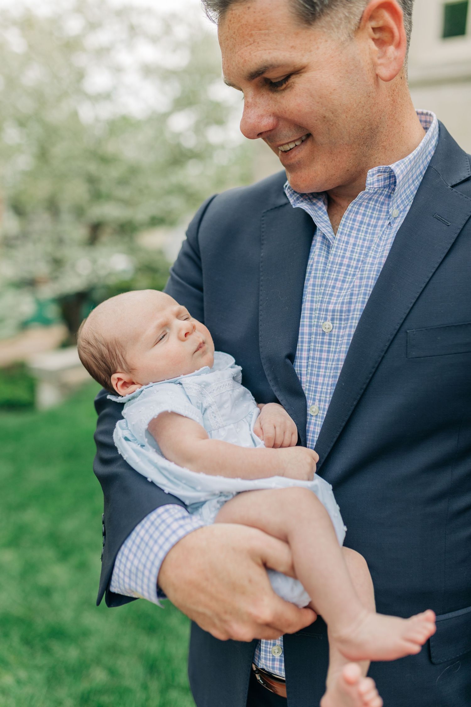 Heartwarming sequence of a baby in light blue being held and admired outdoors.