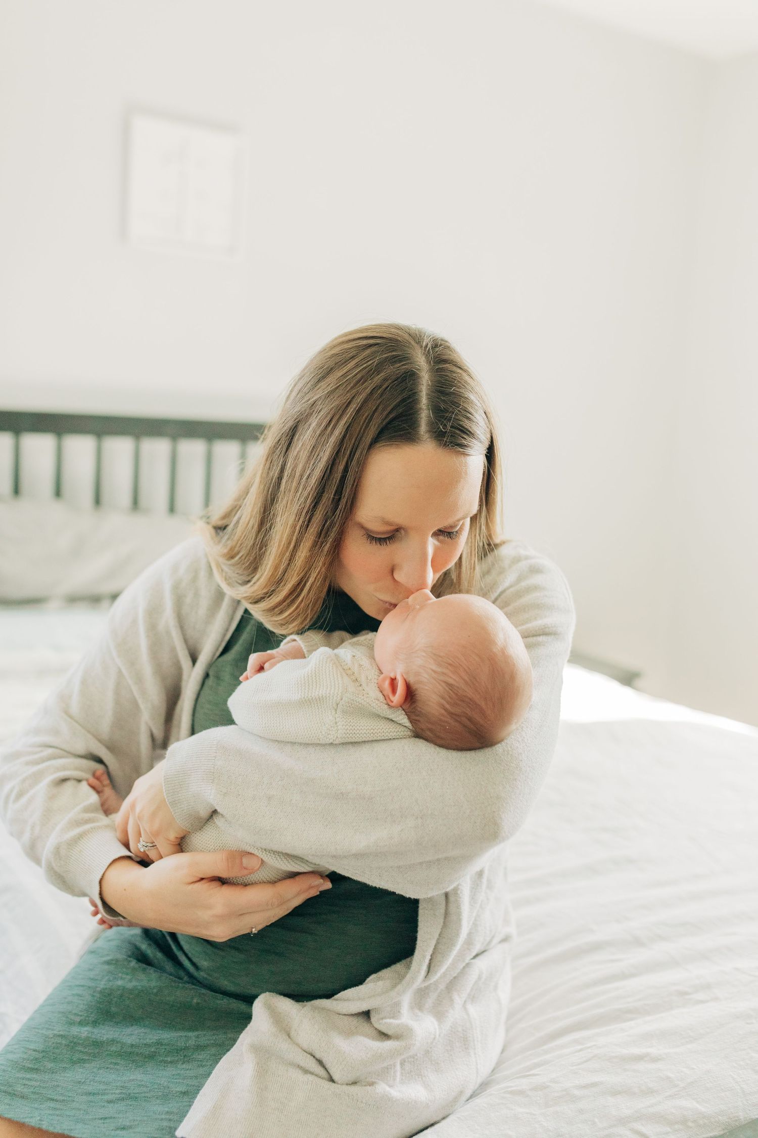 Sweet nurturing moment with a tiny infant wrapped in cozy cream colored blanket.