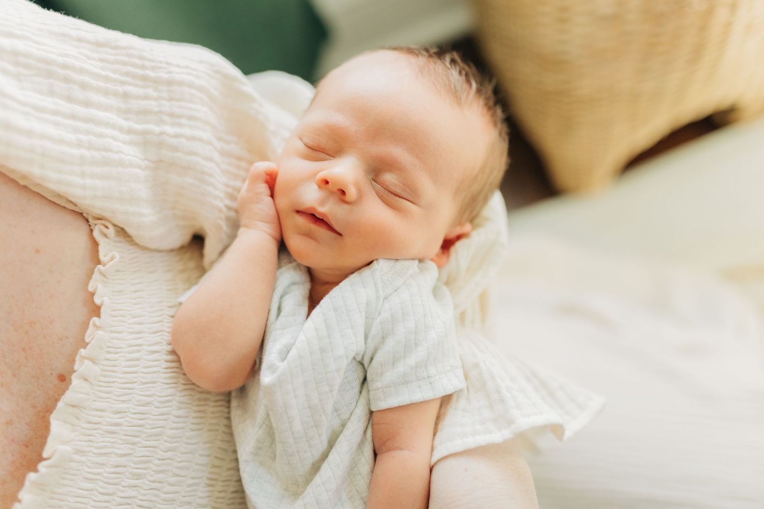 Peaceful sleeping newborn in white clothing resting against soft fabric.