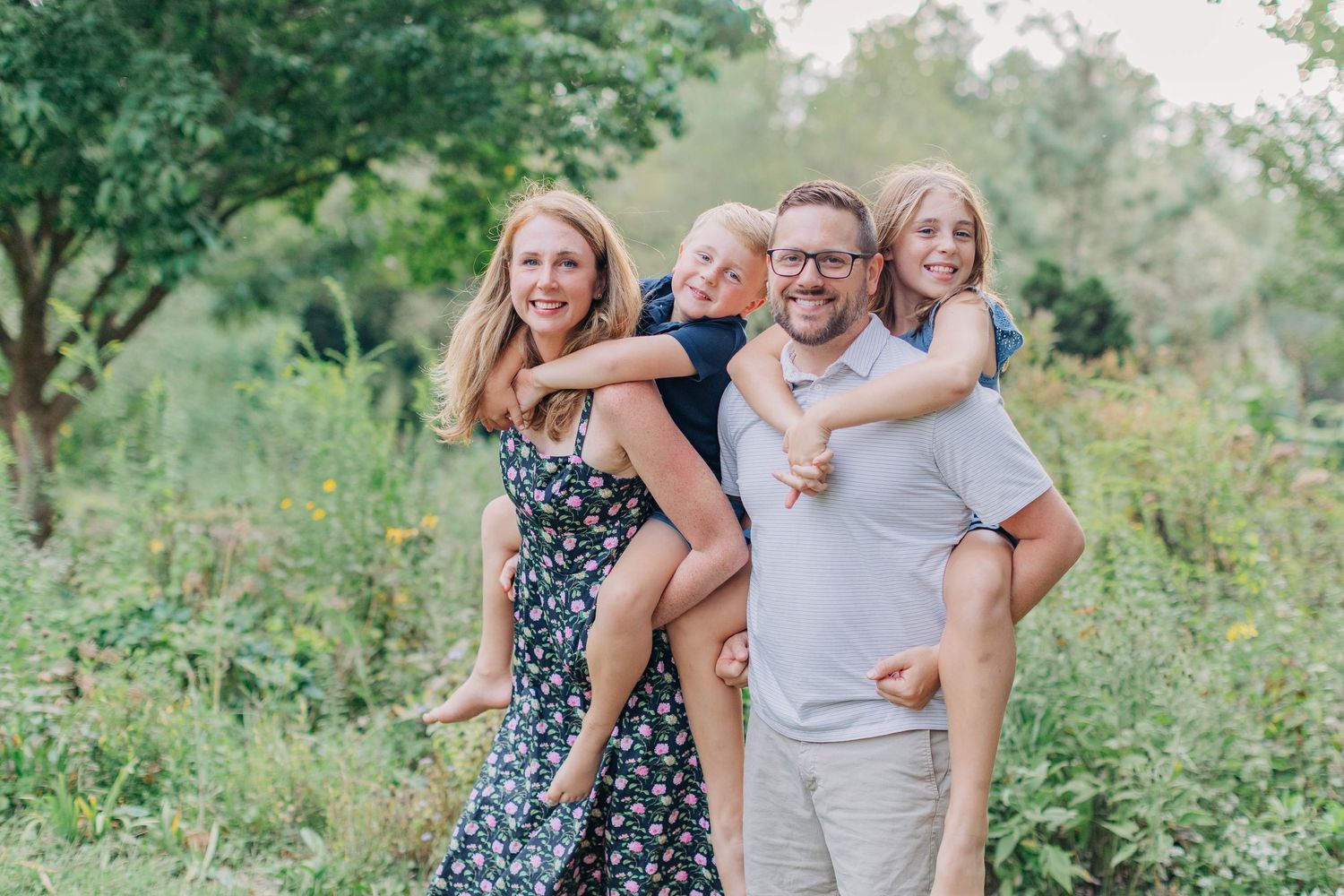A joyful family photo session in a lush garden setting with natural greenery and soft lighting.