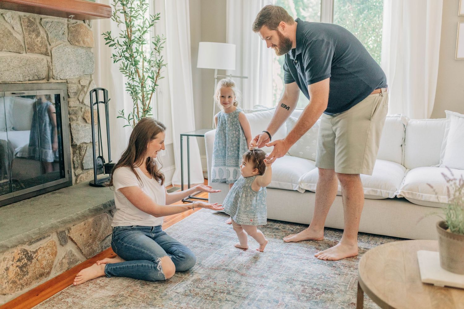 Family playtime in a cozy living room with stone fireplace and large windows.