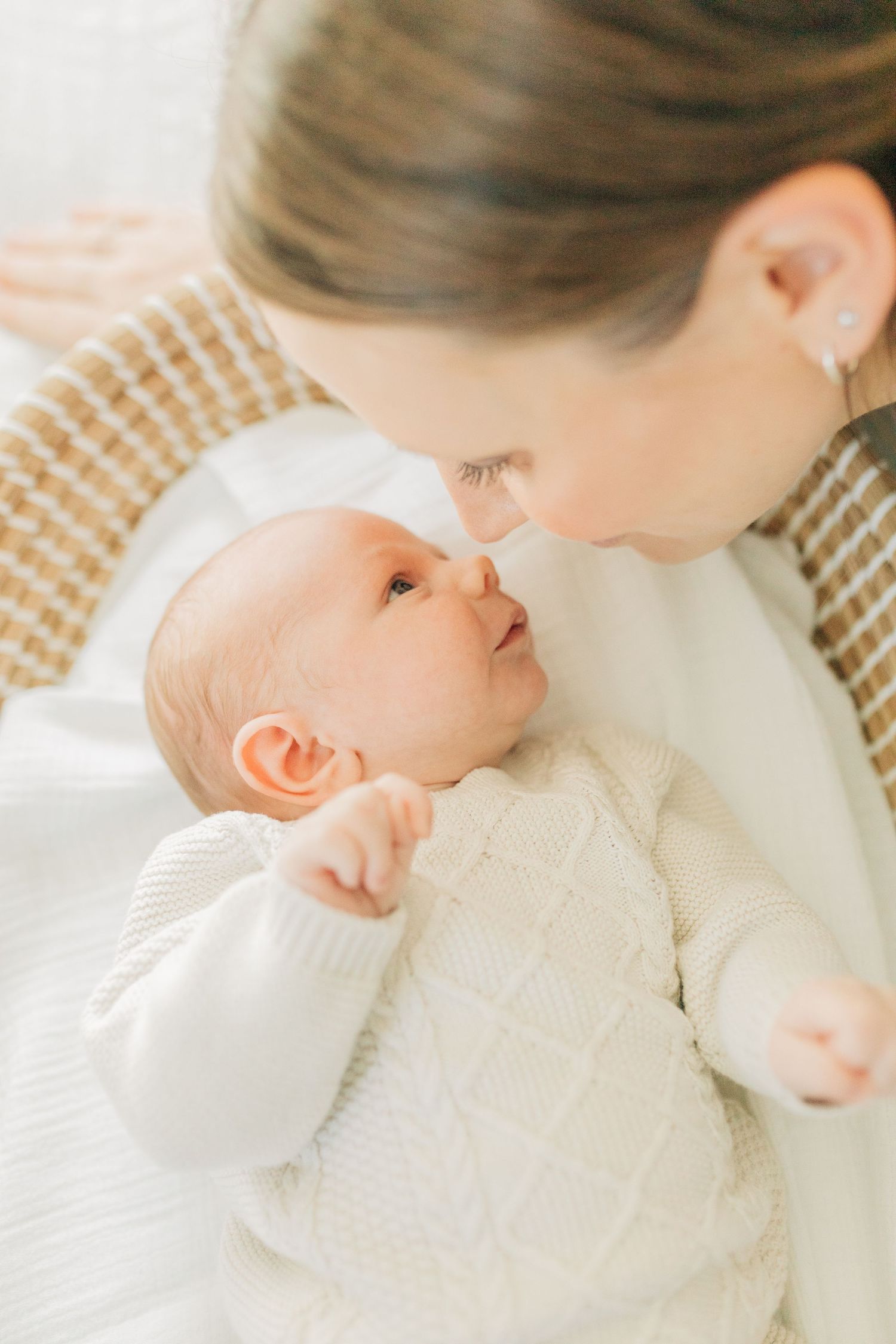 Intimate close-up portraits showing tender moments between parent and infant in cream sweater.