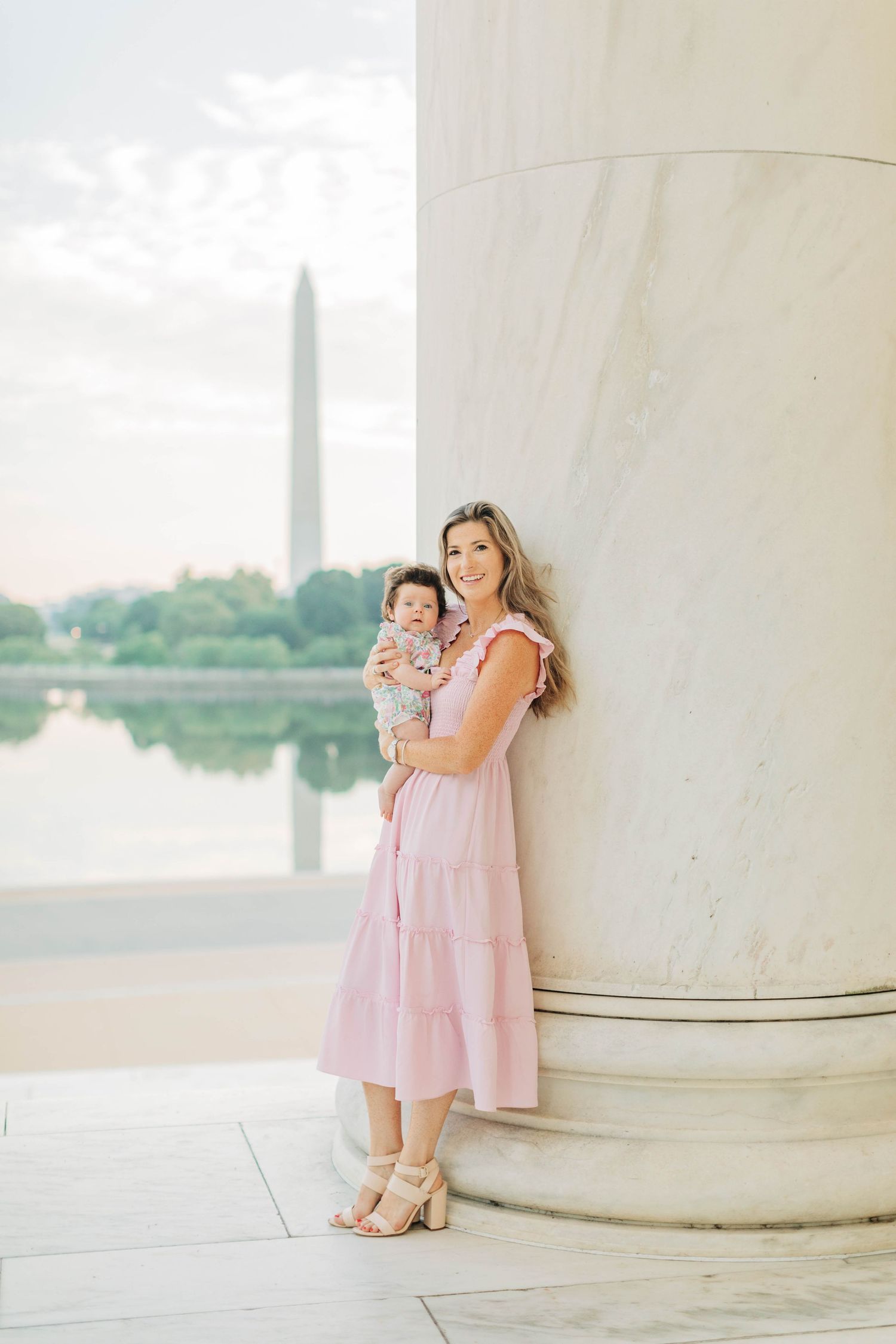 Soft sunset portrait against classical architecture with the Washington Monument in the distance.