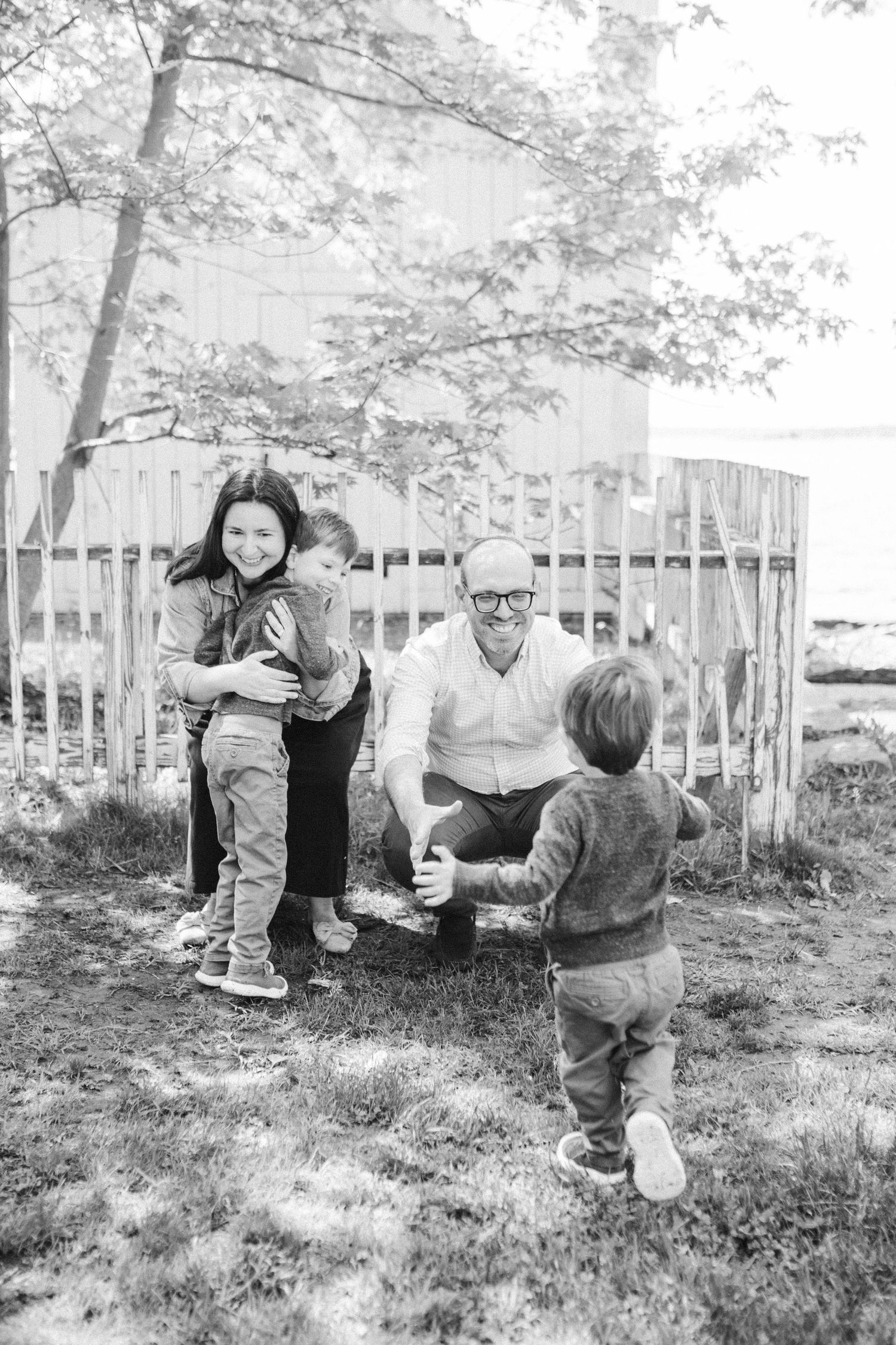 Black and white outdoor family photoshoot with natural interactions in a garden setting.