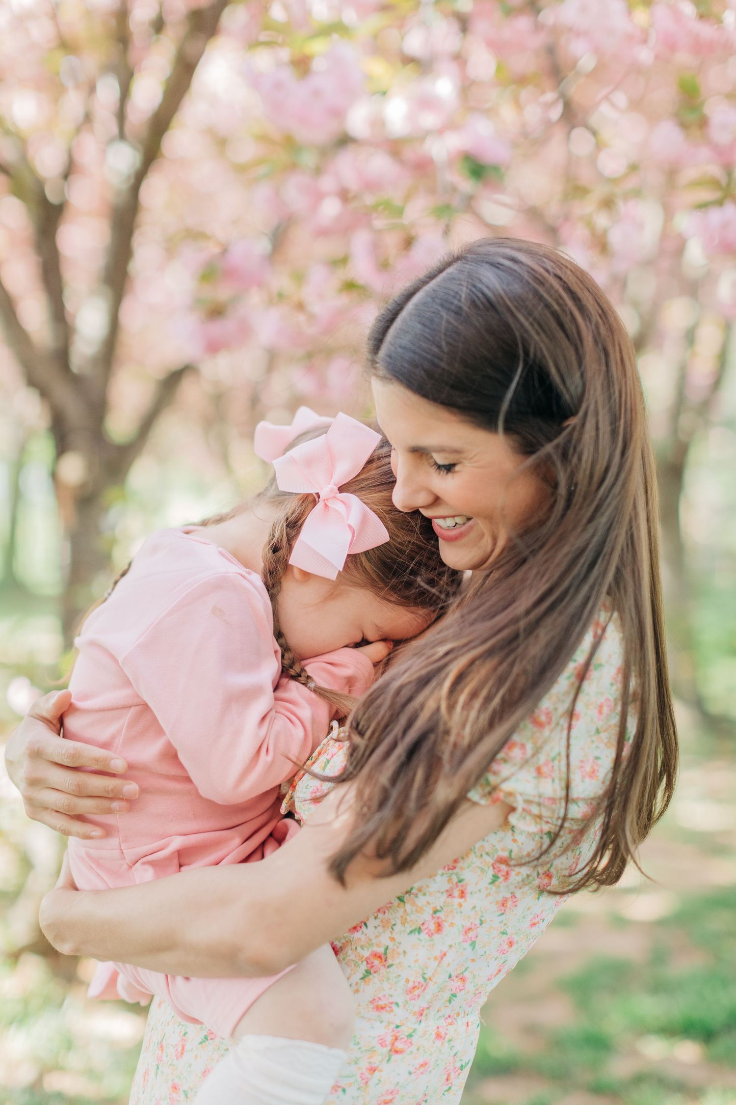 Joyful embrace under pink cherry blossom trees during a spring photoshoot.