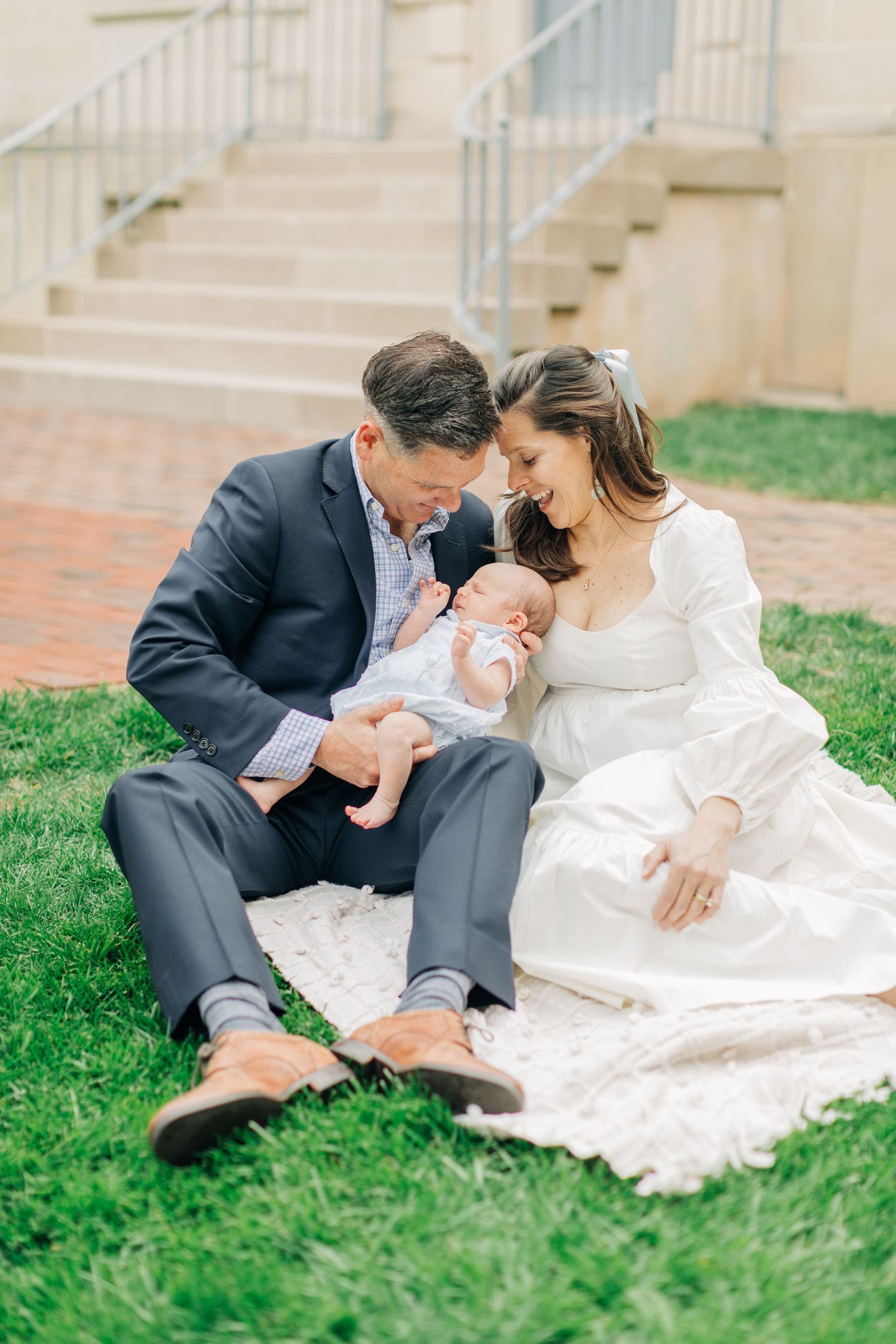 Intimate family portrait session outdoors with baby on white blanket.