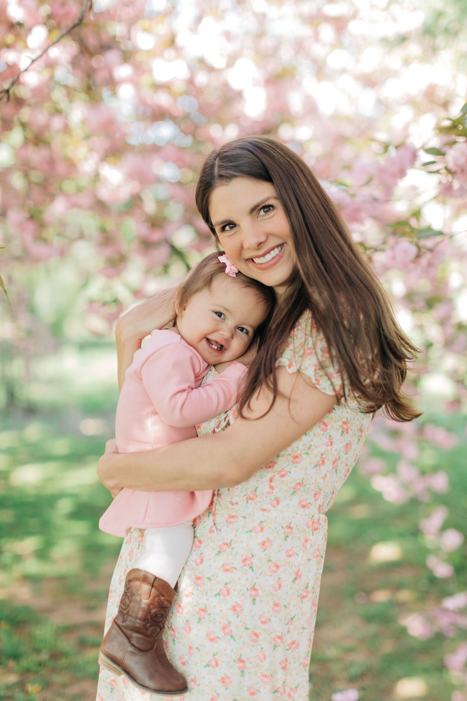 A heartwarming embrace under cherry blossom trees in coordinating spring outfits.