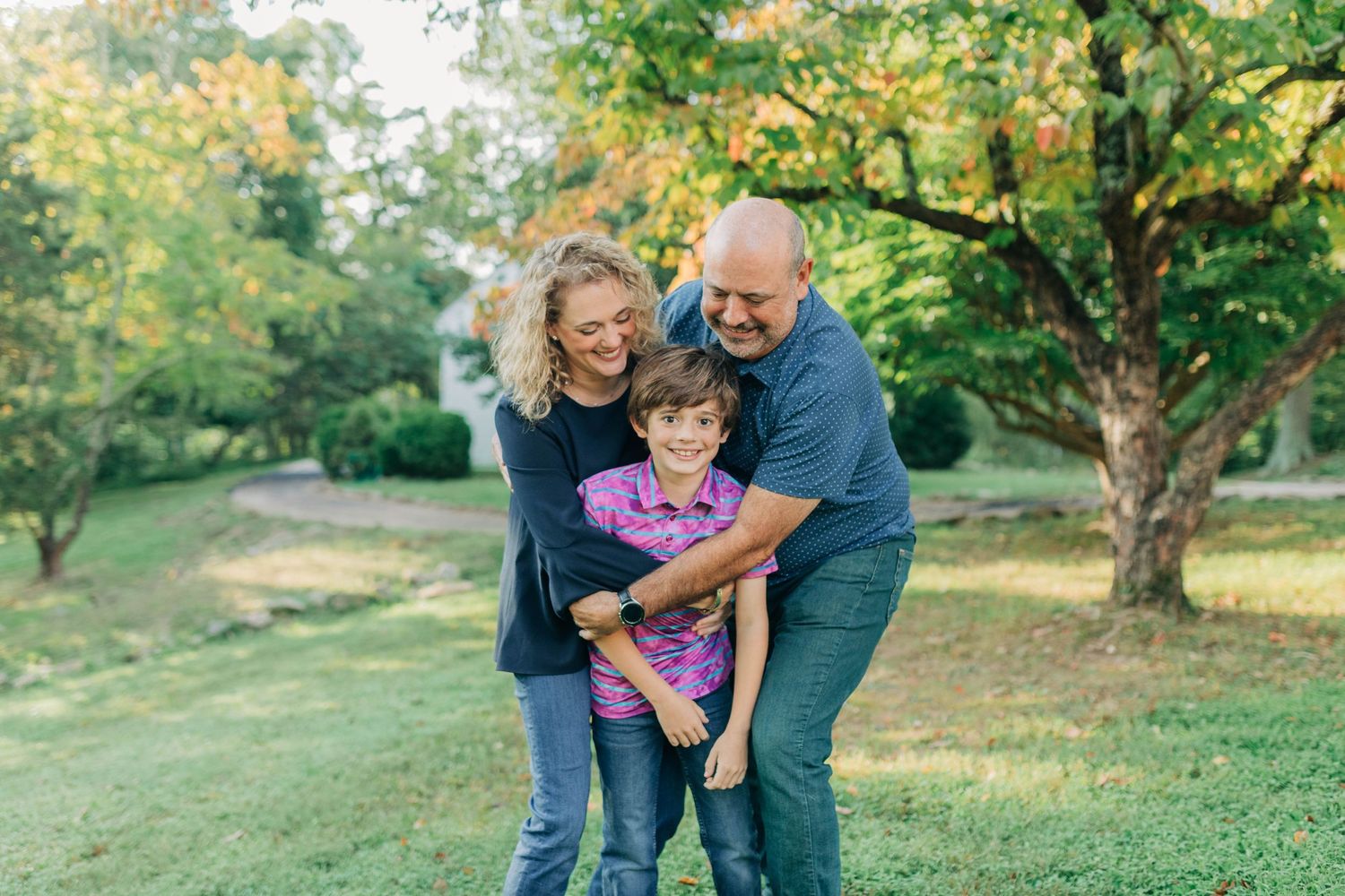 Family members embracing and laughing together in a sunny outdoor setting.