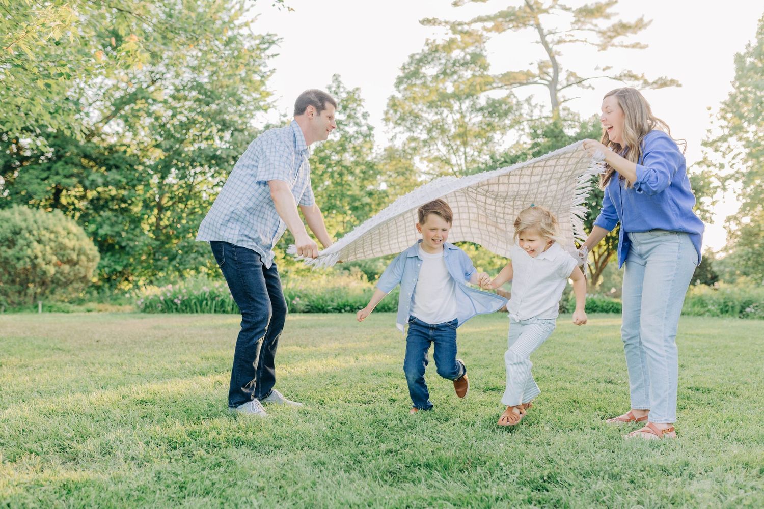 Family playing and running together on a grassy hill during golden hour.