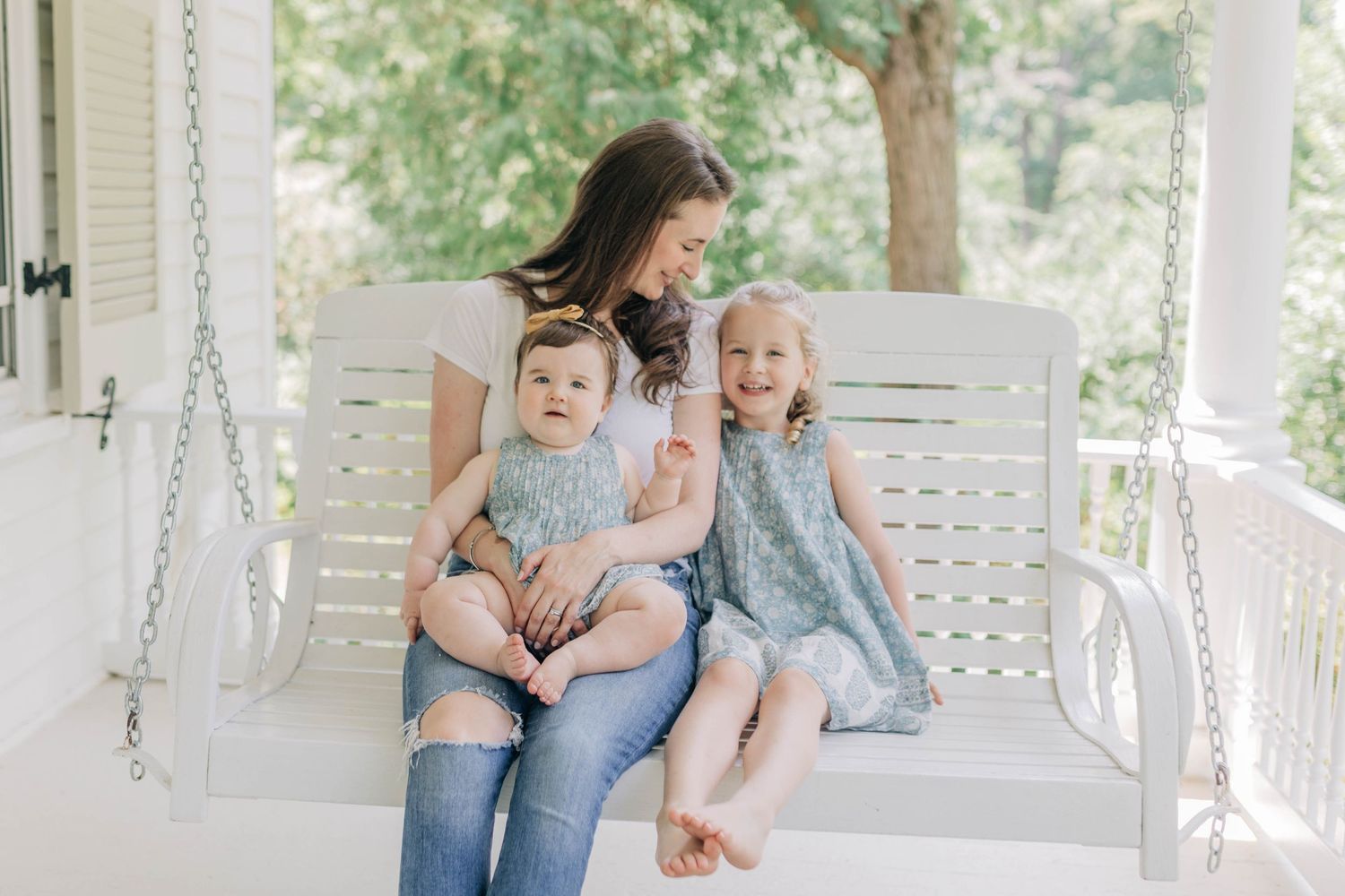 Candid family moments on a white porch swing with greenery in background.