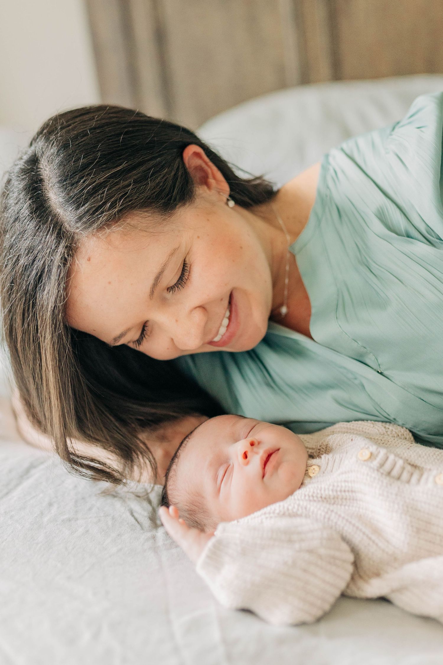 A tender moment between parent and newborn baby resting together on white bedding.