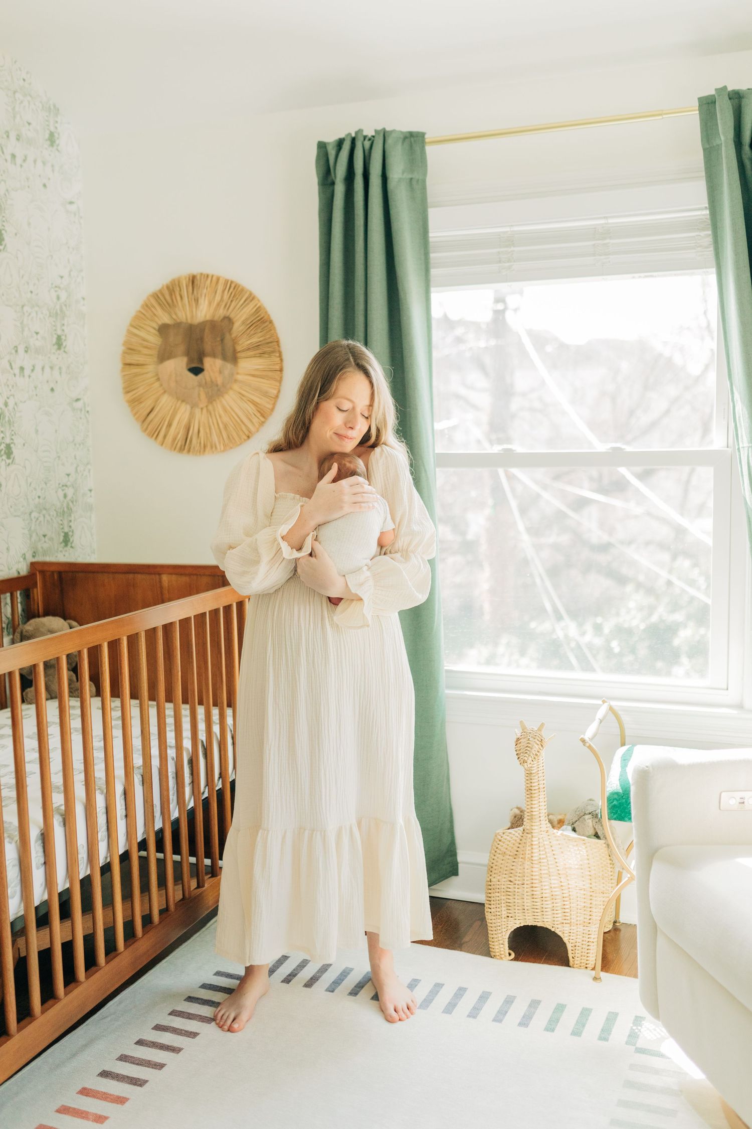 Nursery room with wooden crib, green curtains, and lion wall decor in natural light.