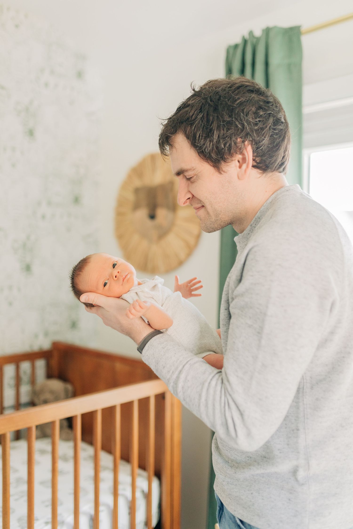 Sweet bonding moment between parent and infant in front of wooden crib.