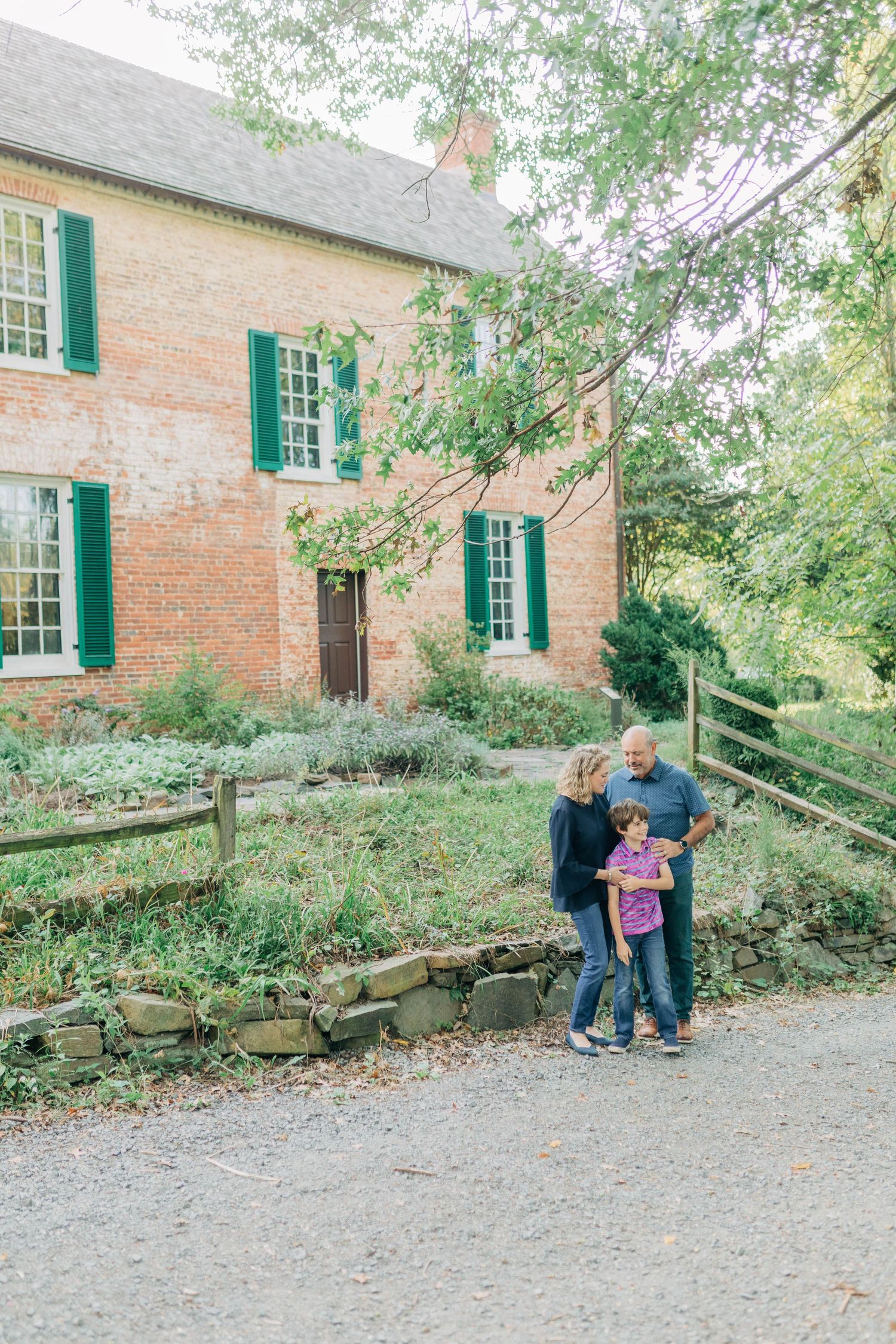 Family moment photographed outside a historic brick building with green shutters.