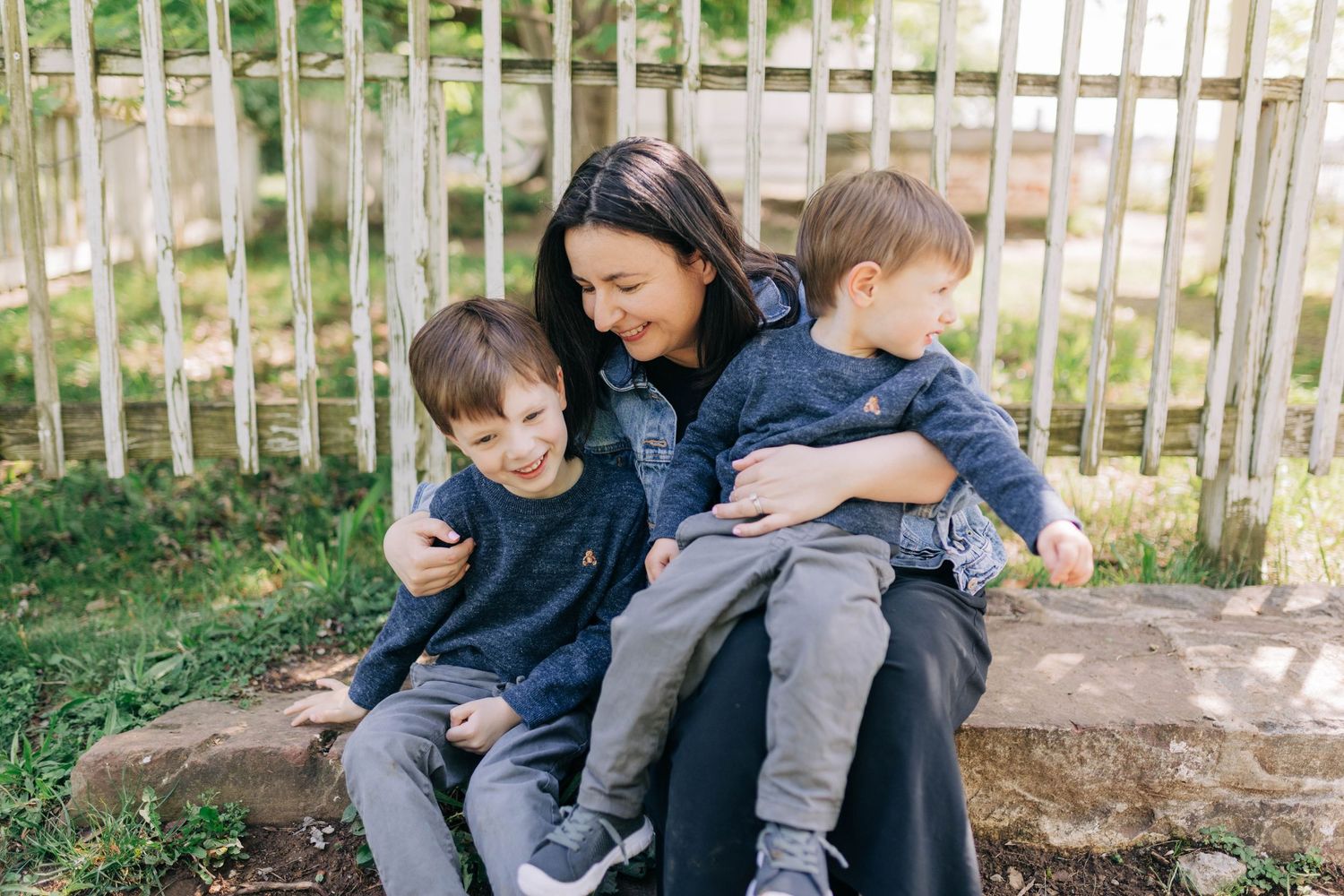 Family sitting together on wooden steps outdoors in casual clothing.