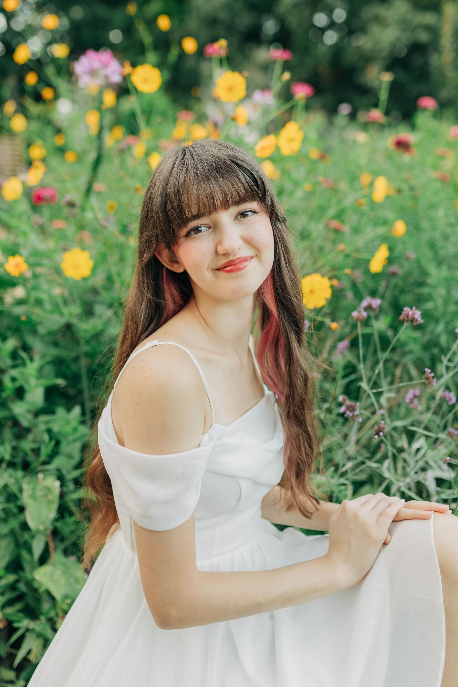 A dreamy photoshoot in a garden with yellow and pink flowers creating a vibrant natural backdrop.