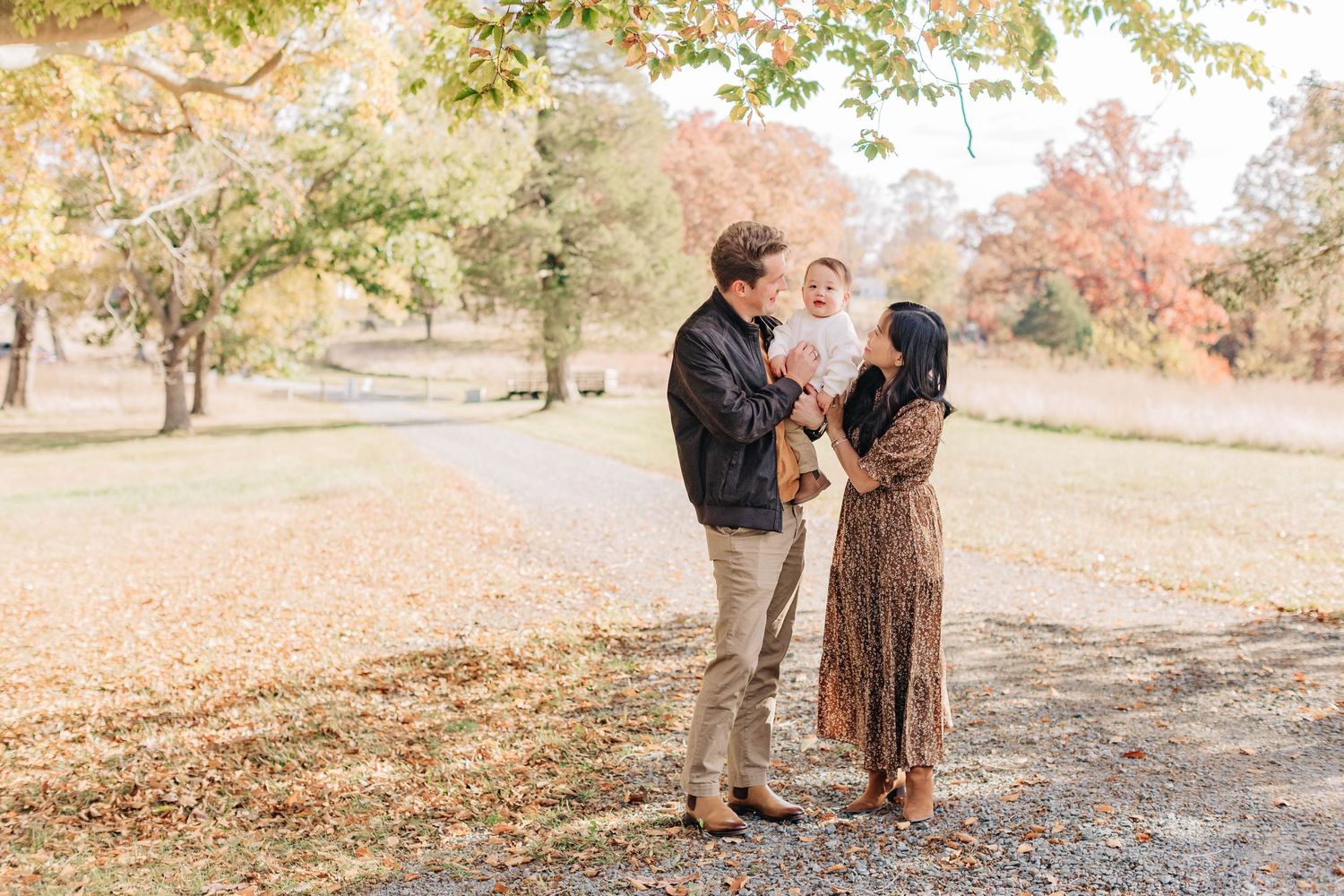 Couple enjoying a romantic autumn photoshoot outdoors with fallen leaves and natural scenery.