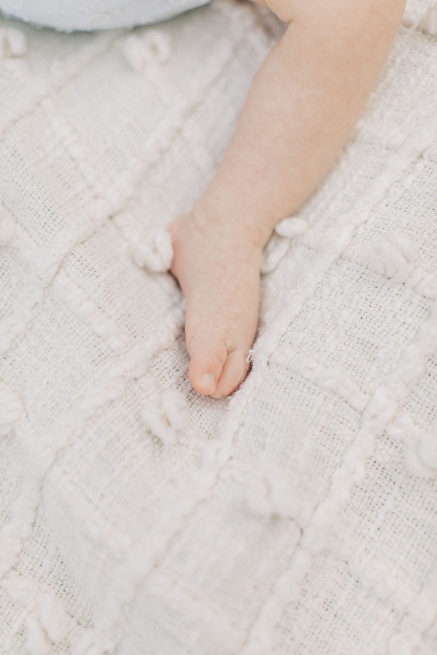 Close-up of tiny baby feet on white lace fabric.
