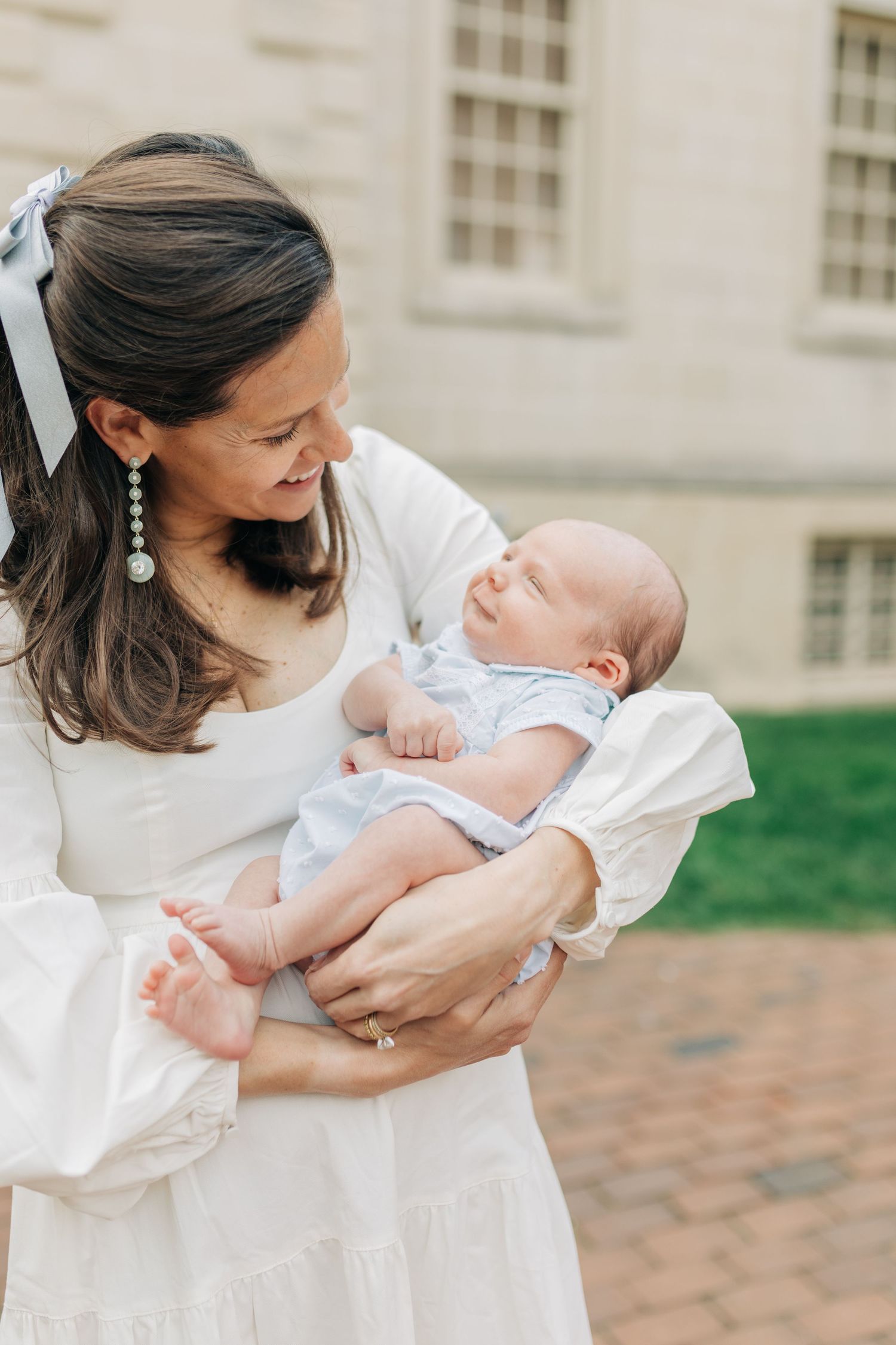 Woman in white dress holding and bonding with infant on stone steps.