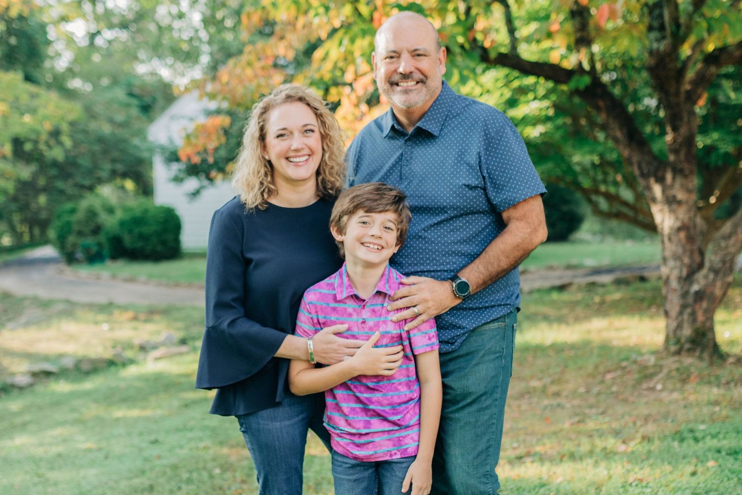 Family enjoying a playful moment together outdoors in a lush green park setting during autumn.
