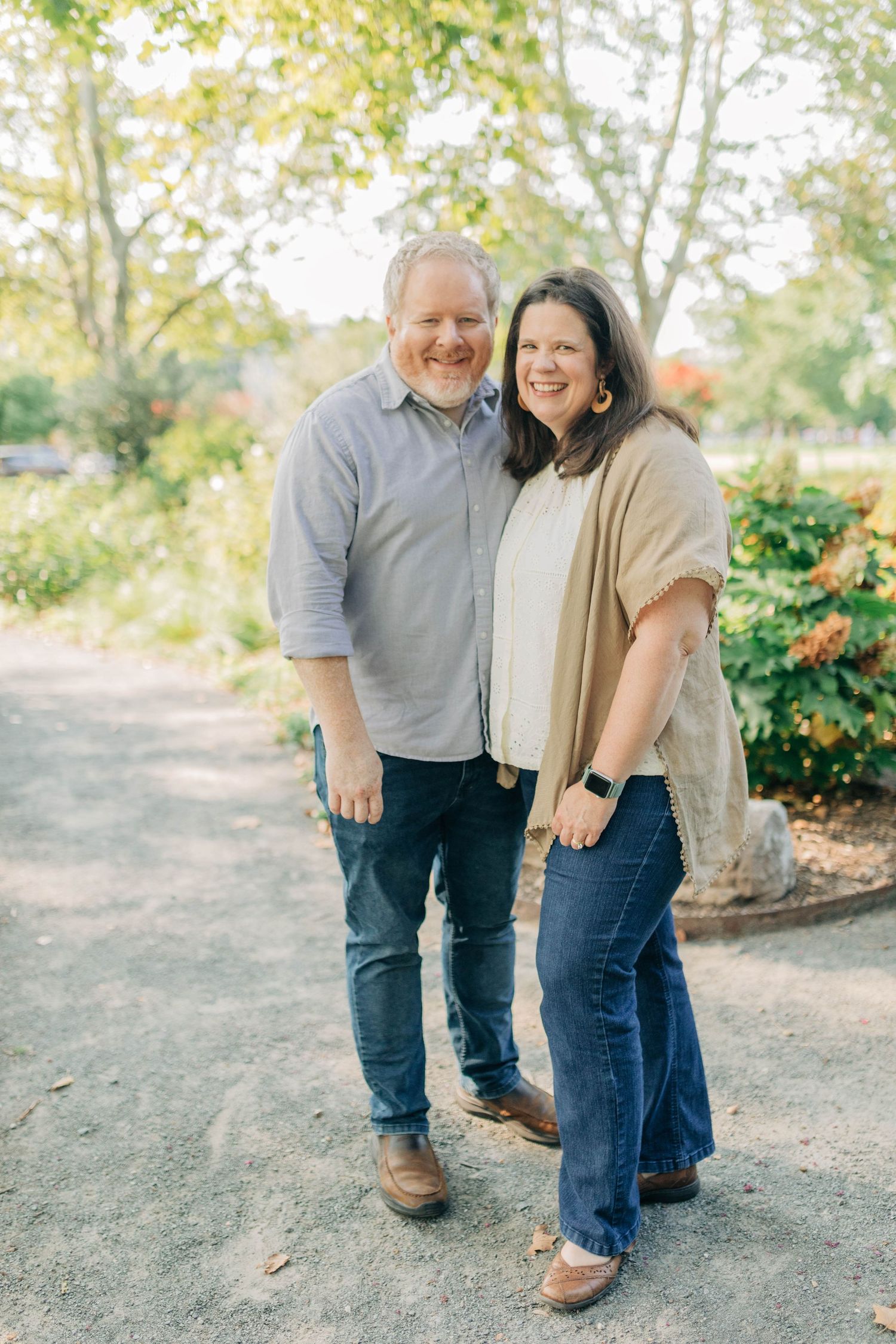 Couple sharing a joyful moment together on outdoor path with trees in background.