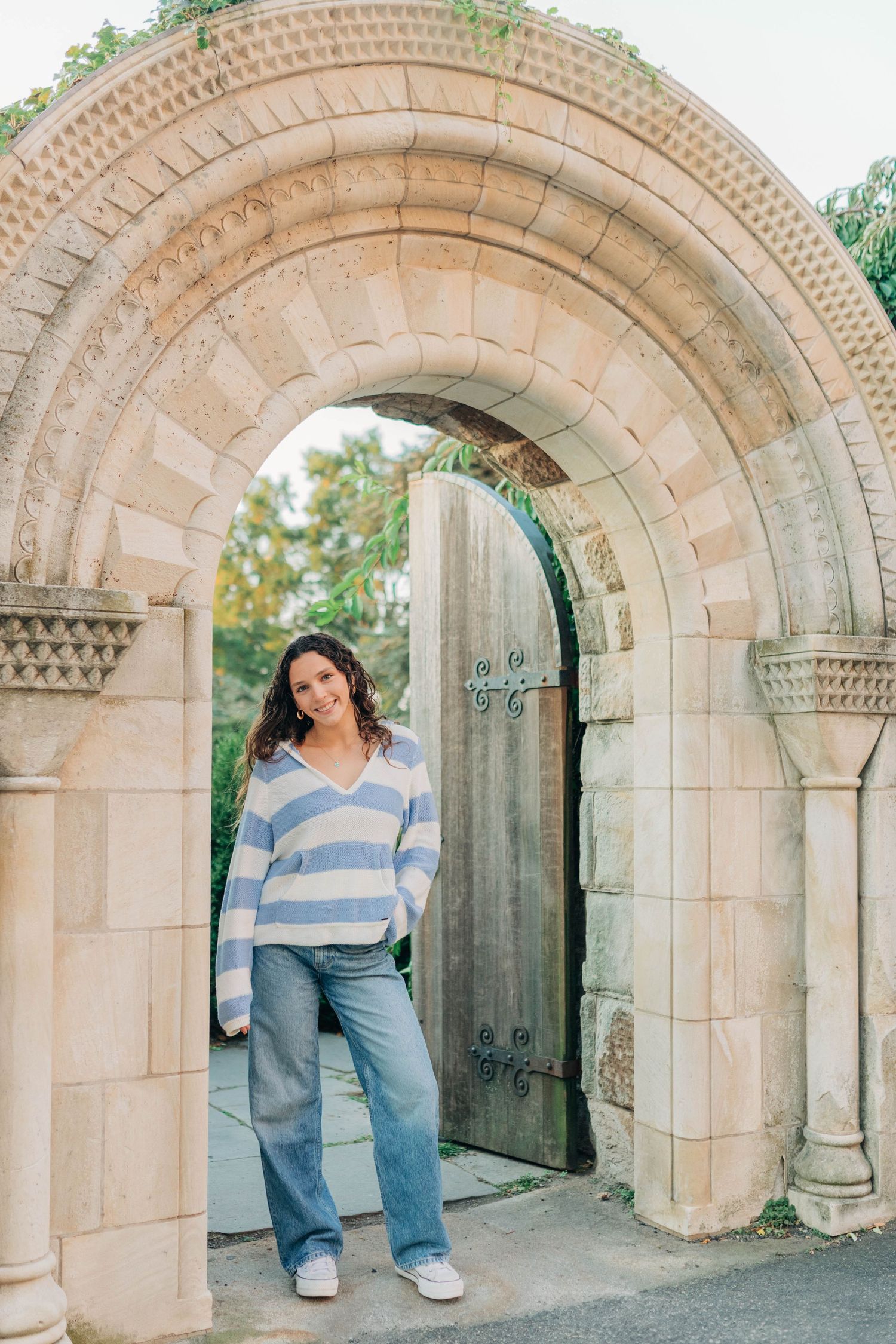 Stone archways with ornate architectural details create a dramatic backdrop for casual portraits.