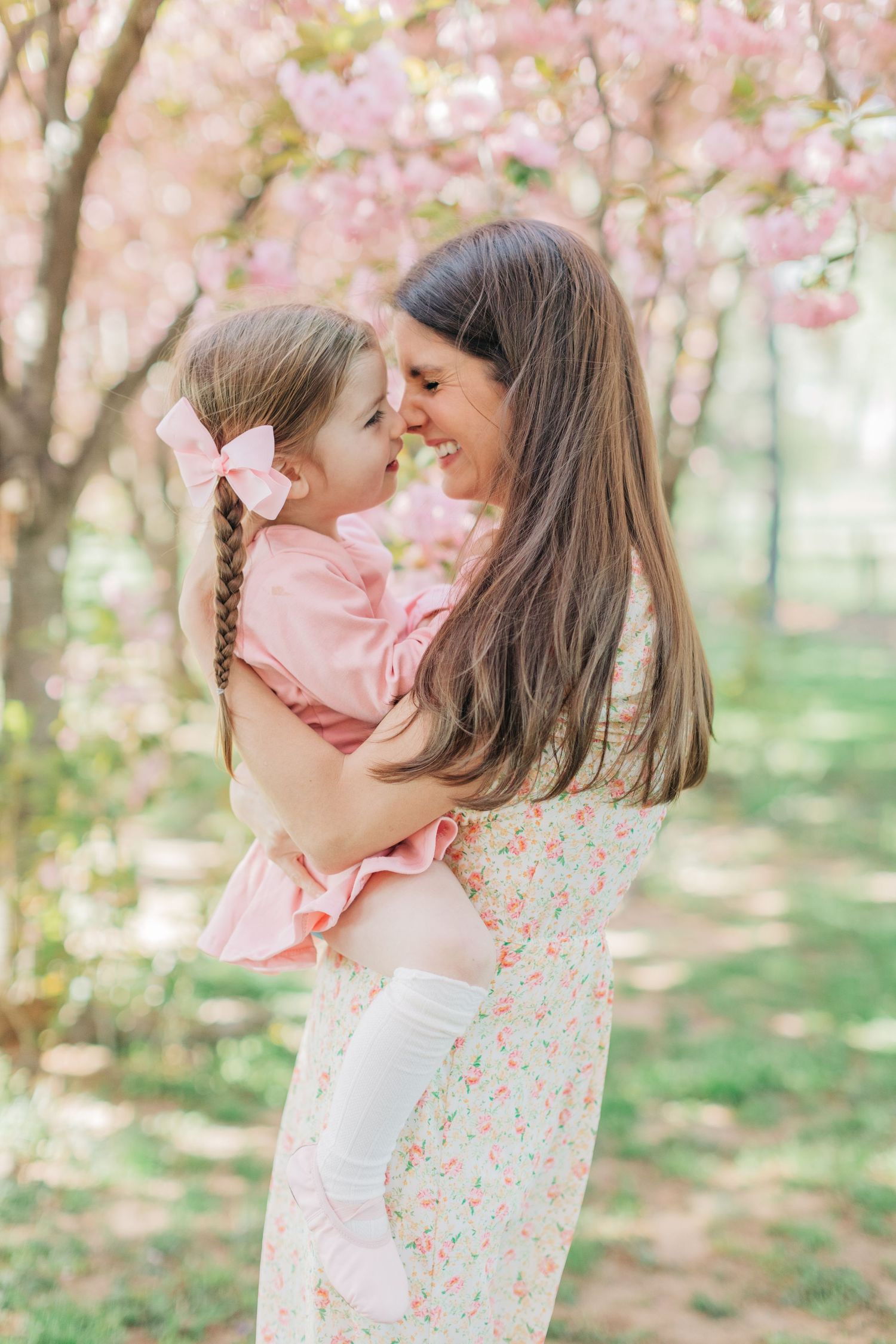Sweet candid moment captured between parent and child amidst flowering cherry trees.