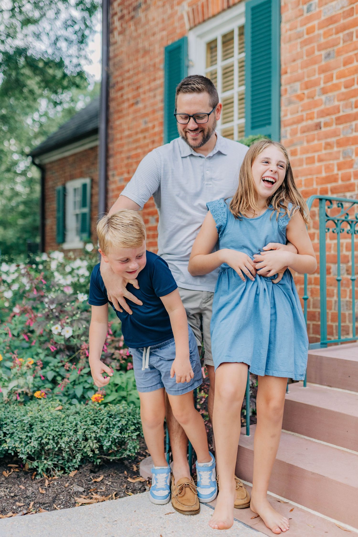 A playful family moment captured on brick steps with everyone laughing together.