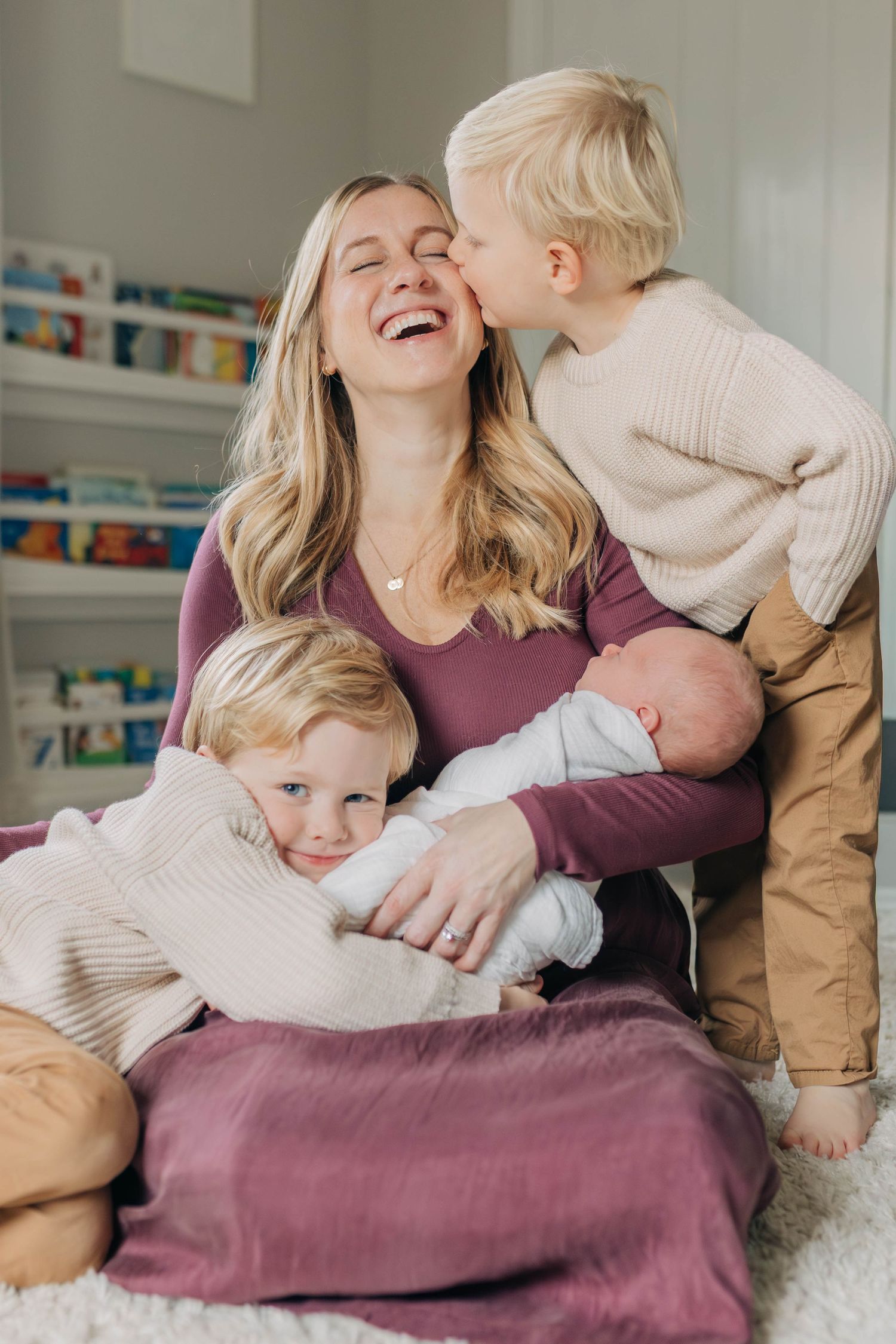 Joyful family moment with children and baby on white carpet.