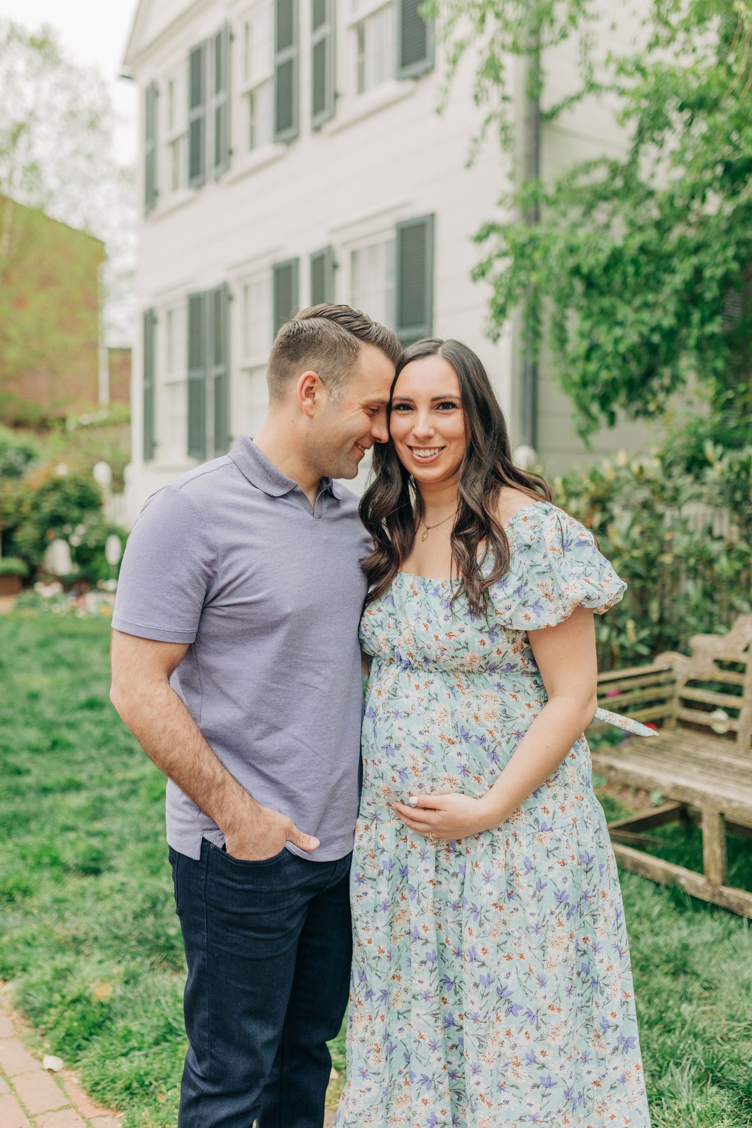 A couple shares intimate moments in a garden setting wearing coordinated casual outfits.