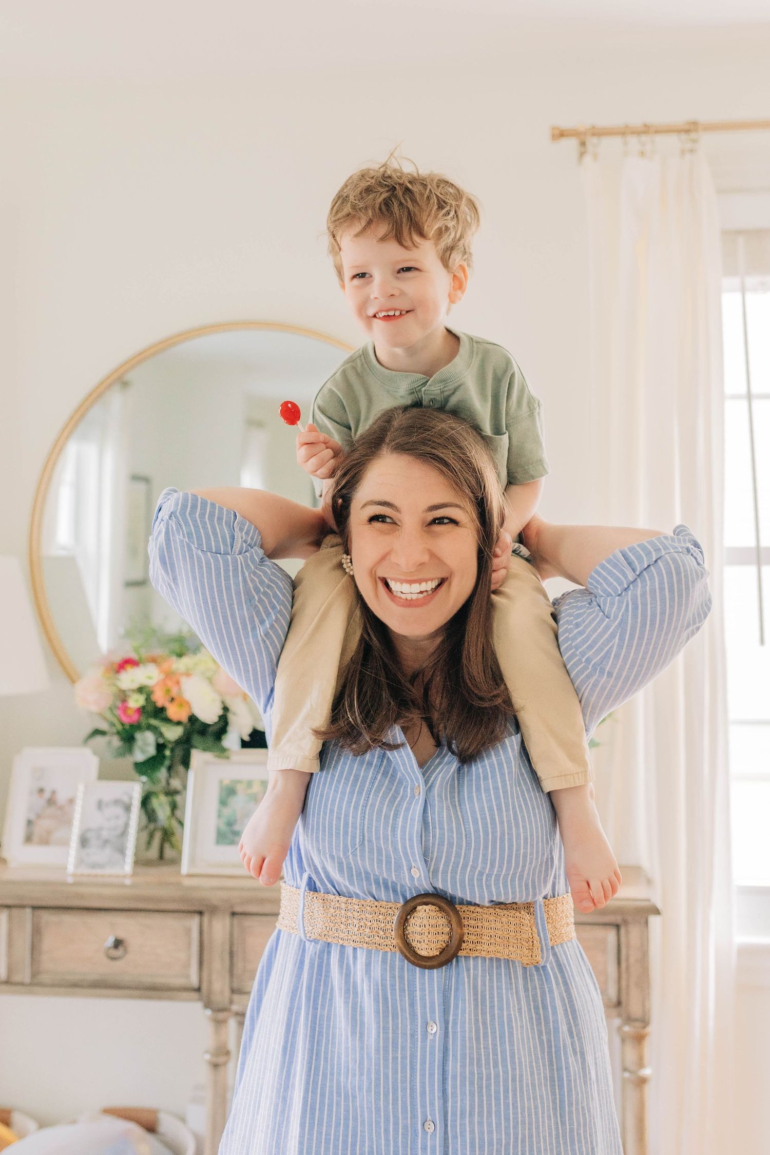 Joyful moment captured in a bright room with a decorative round mirror and floral arrangement.